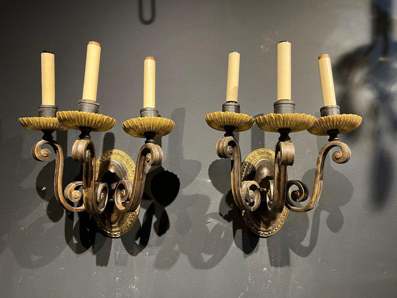 A pair of circa 1920’s Brown patinated bronze three lights Caldwell sconces, with unusual scrolled arms 