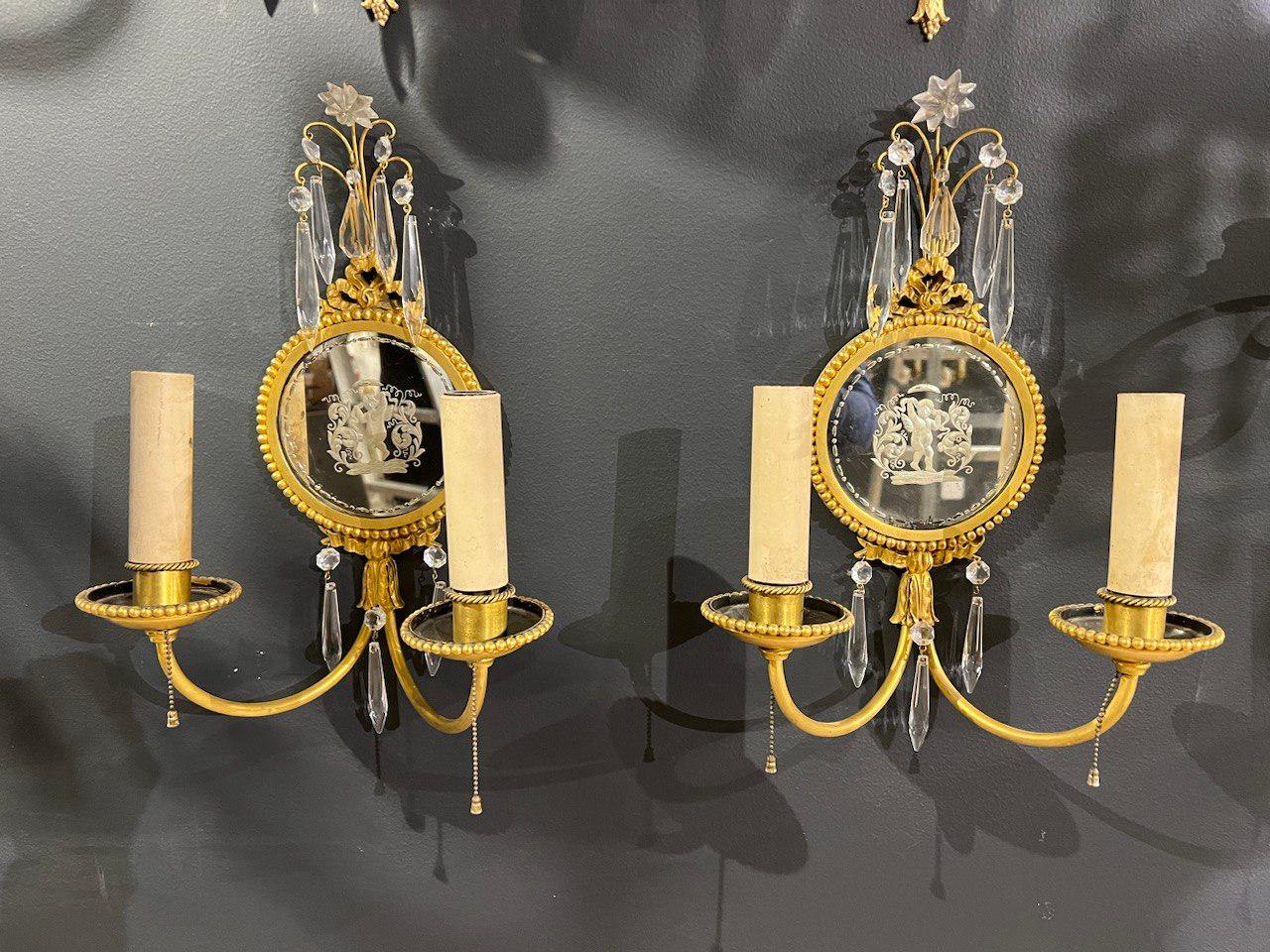 A pair of 1920’s Caldwell gilt bronze and mirrored backplate sconces with cherubs