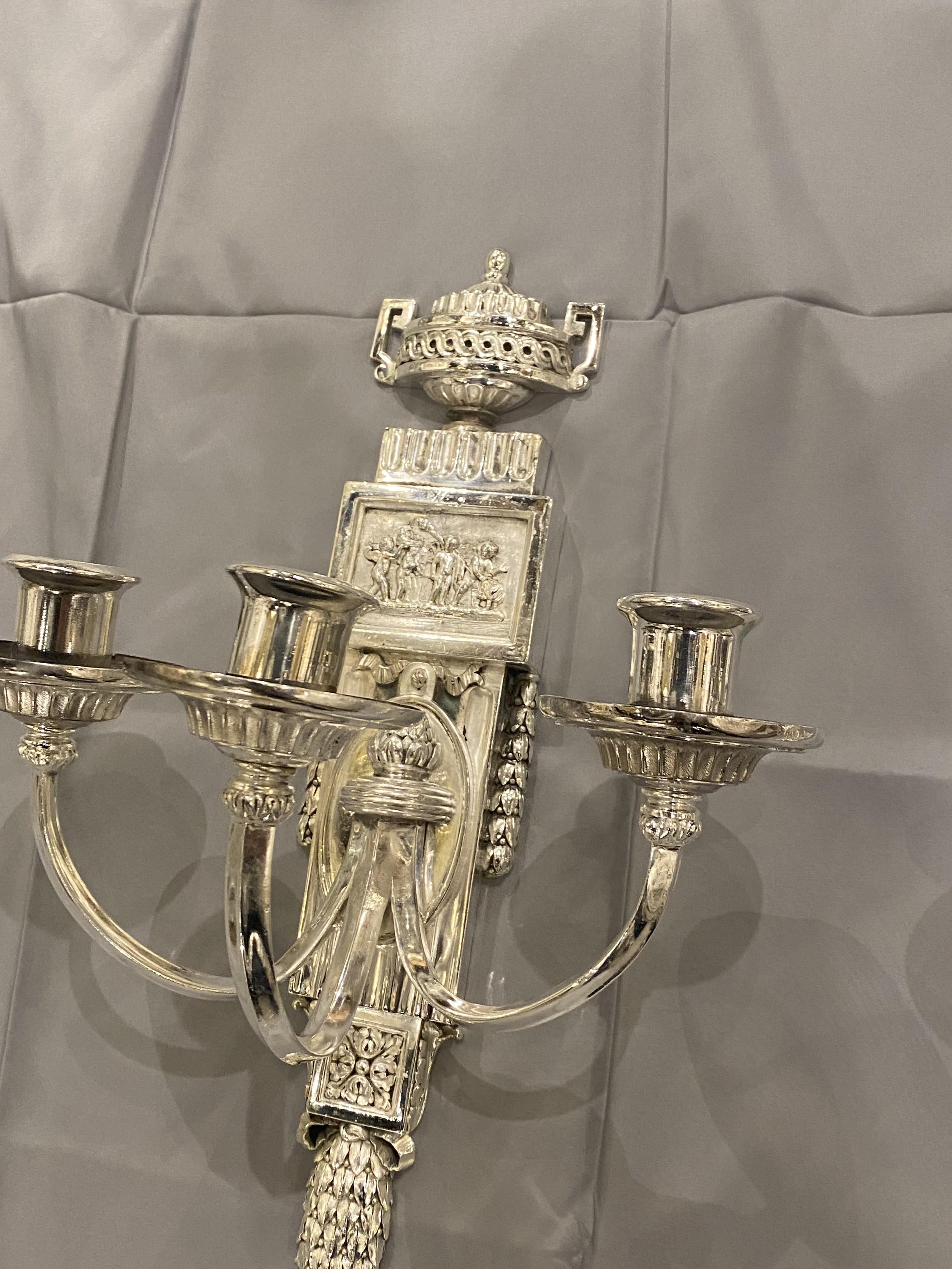 A pair of circa 1920's Caldwell silver plated three lights sconces with cherubs atop.
