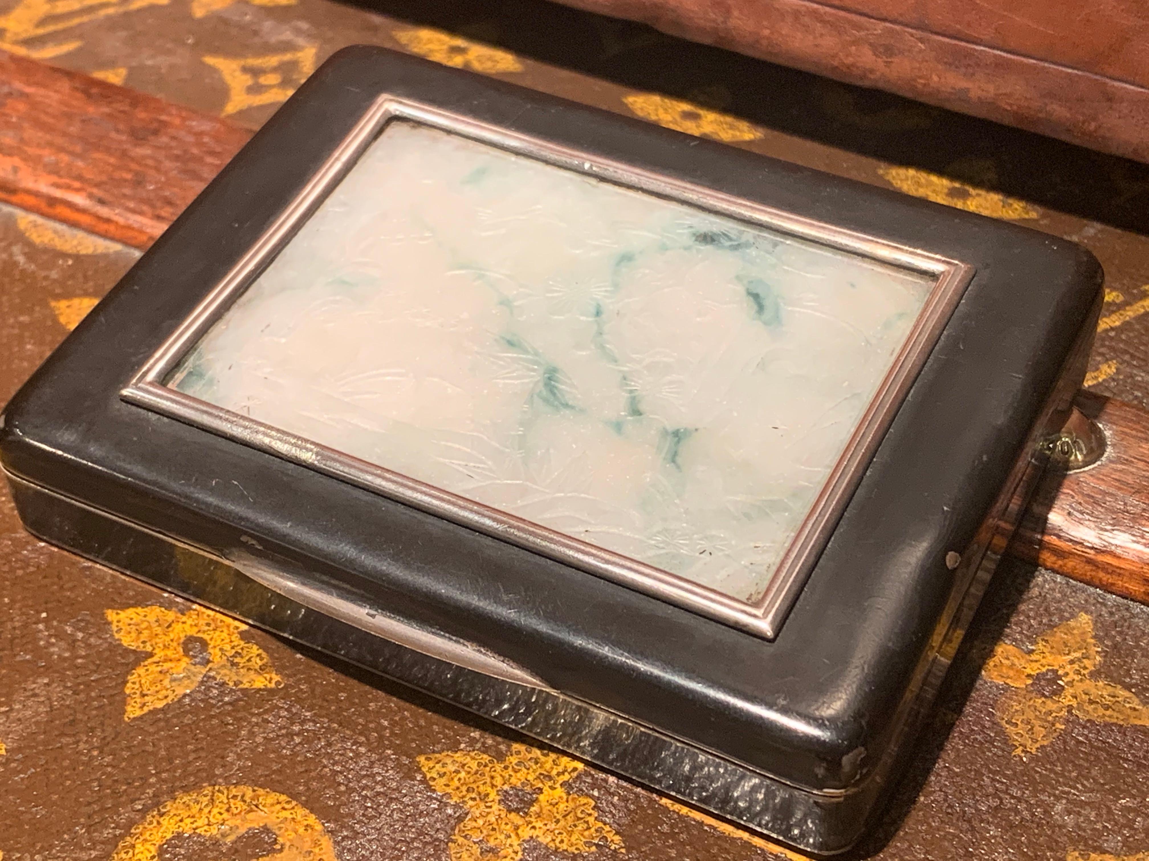 Rare Cartier (London) Black Enamelled Box with a Jade Piece on the Lid.

The Jade is slightly engraved with what seems to be a Natural theme (Trees, flowers).
This Box could have been used as a Cigarette Box

The inside of the Lid, is engraved