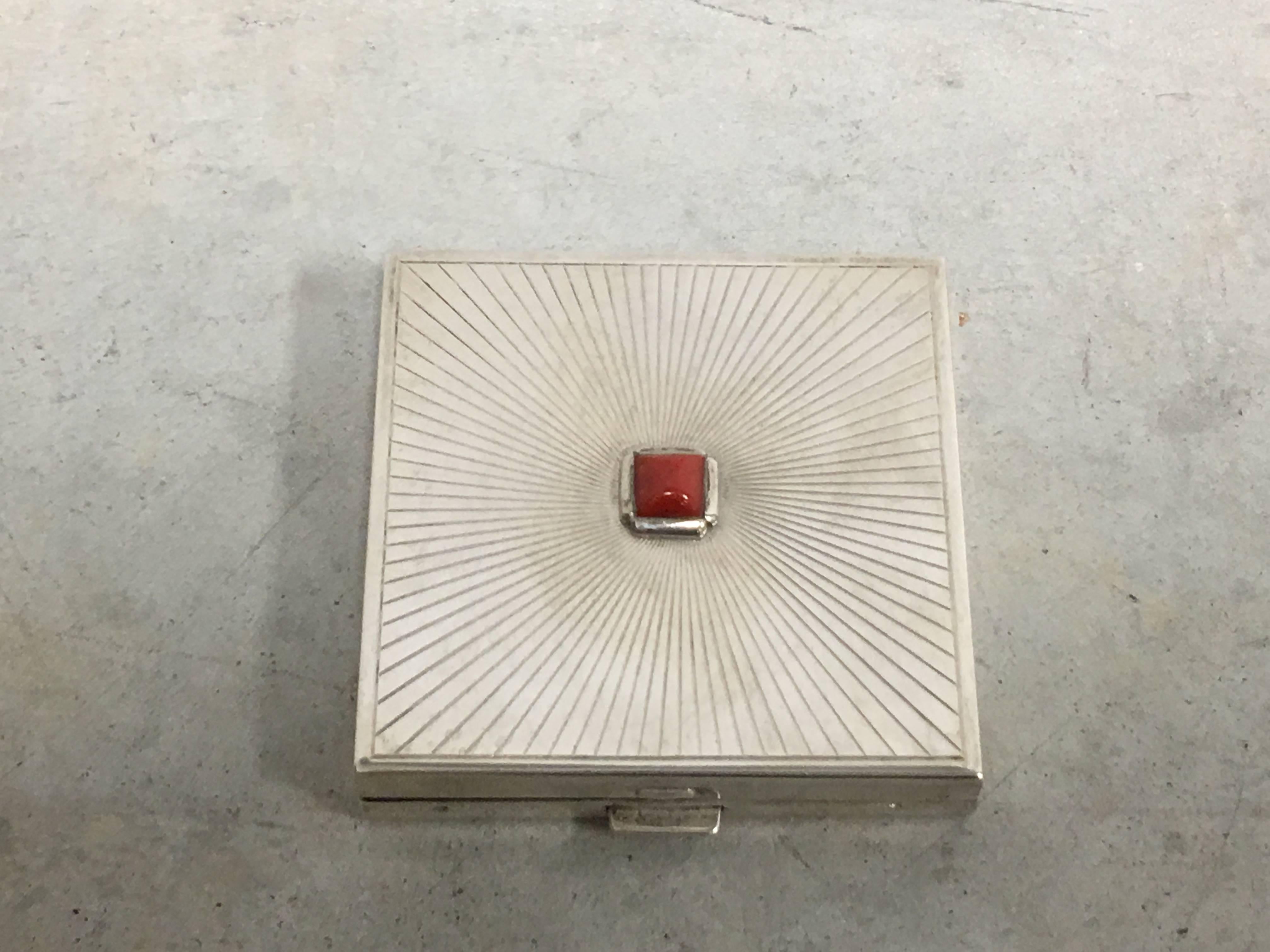 Offered is a stunning, Cartier sterling silver compact with a red carnelian gem inset, circa 1920. Cartier captures the true essence of Art Deco sophistication with this exquisite sterling silver box. Such diminutive objet d'art are found most often