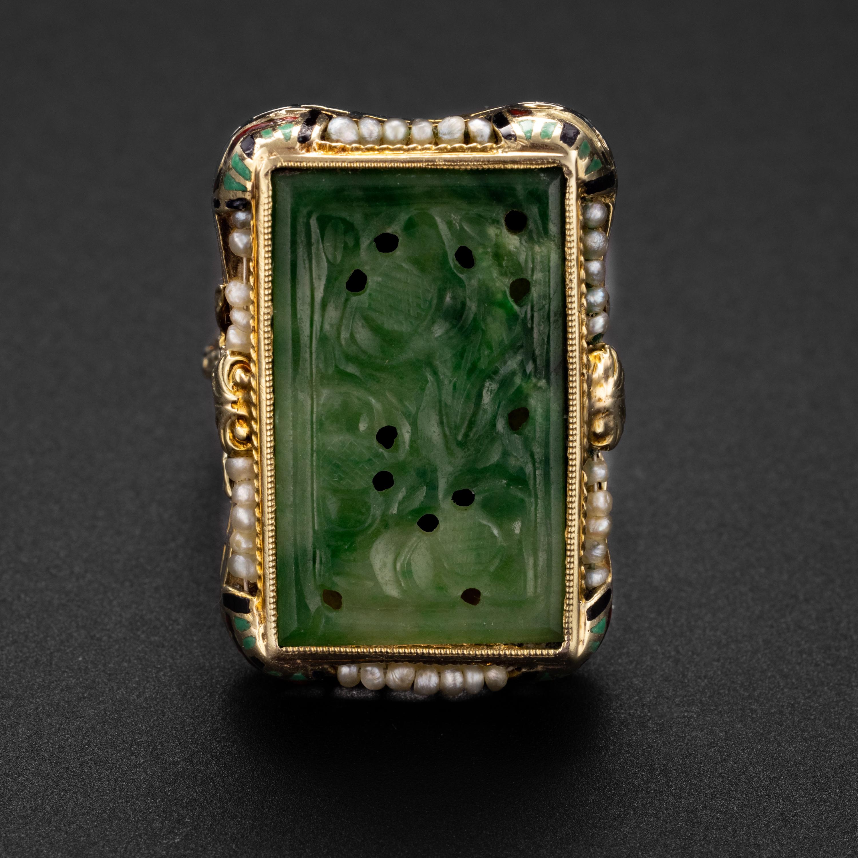 An emerald green plaque of natural and untreated Burmese jadeite jade, carved and pierced in a floral motif, is showcased within an ornately styled 14K gold ring.  The jade measures 21.1mm x 13mm x 1.3mm. The face of the ring is 25.74mm x 18mm.