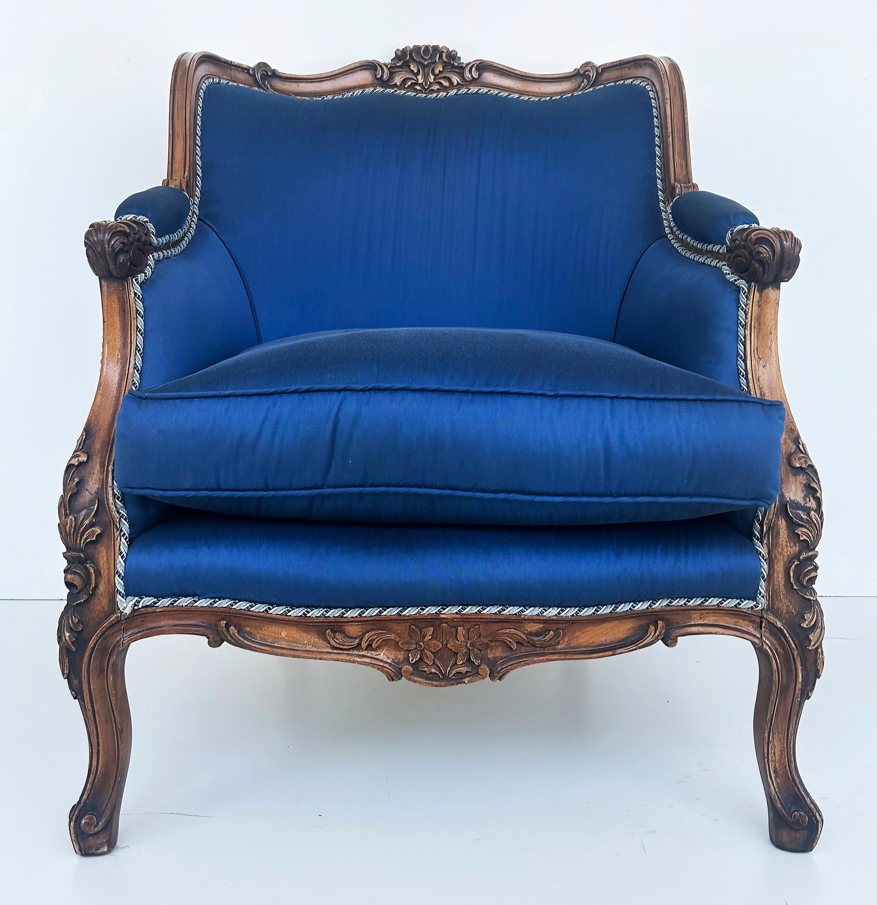1920s Carved Walnut French Bergeres Armchairs Upholstered in Silk, a Pair 

Offered for sale is a pair of  French hand-carved Walnut Bergere club chairs that have been beautifully upholstered in blue silk with contrasting welting.  These wonderful