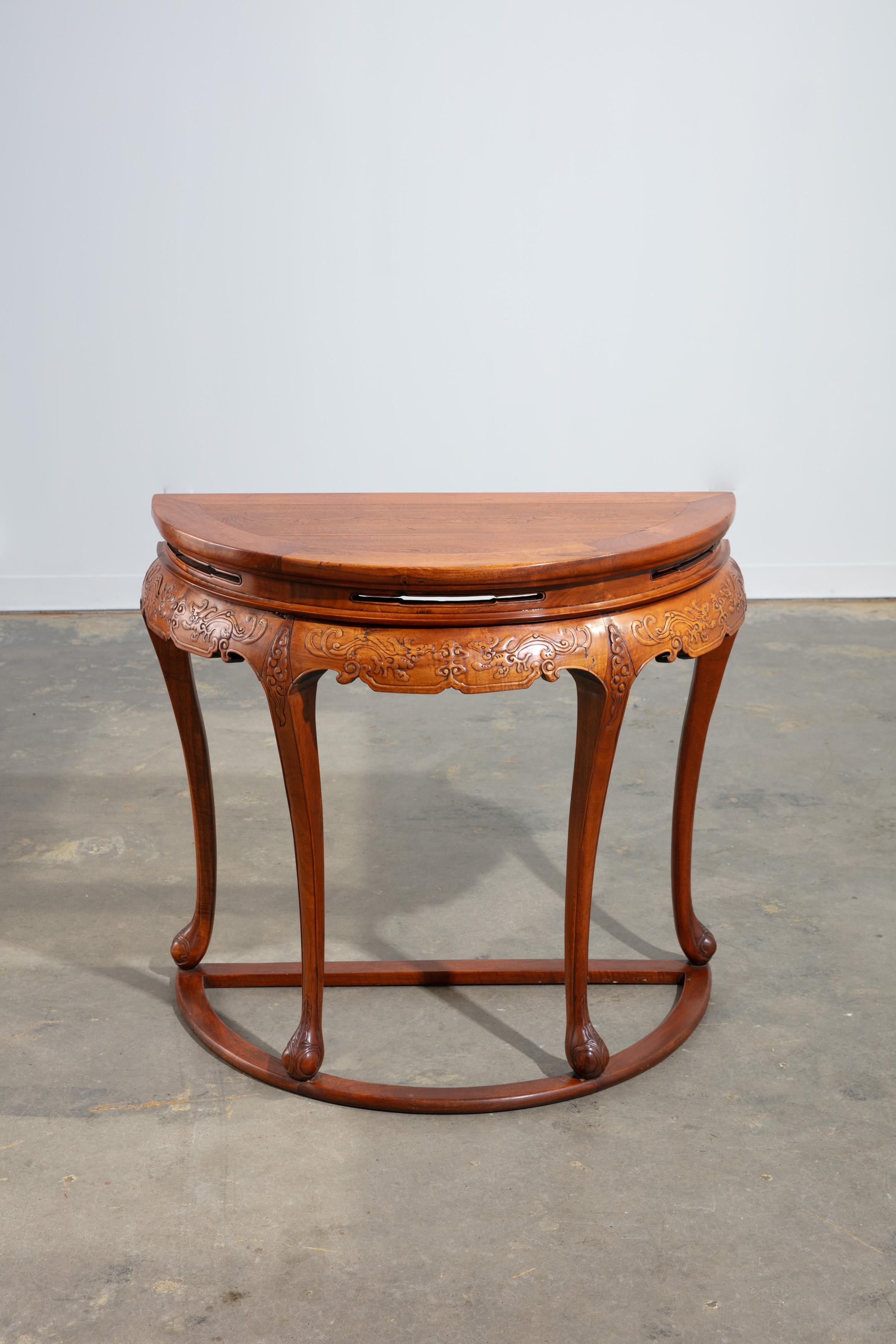 Vintage 1920's carved wood Chinese demi-lune/console table with beautifully curved design and intricate wood carvings along the apron including floral and scroll motifs. Supported by 4 slender cabriole legs with a graceful downward curve and small