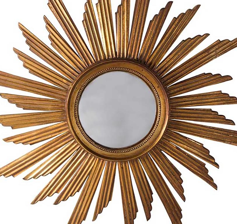 This golden colored carved wooden sunburst mirror has reeded decorative detail. This piece features a convex mirror plate.