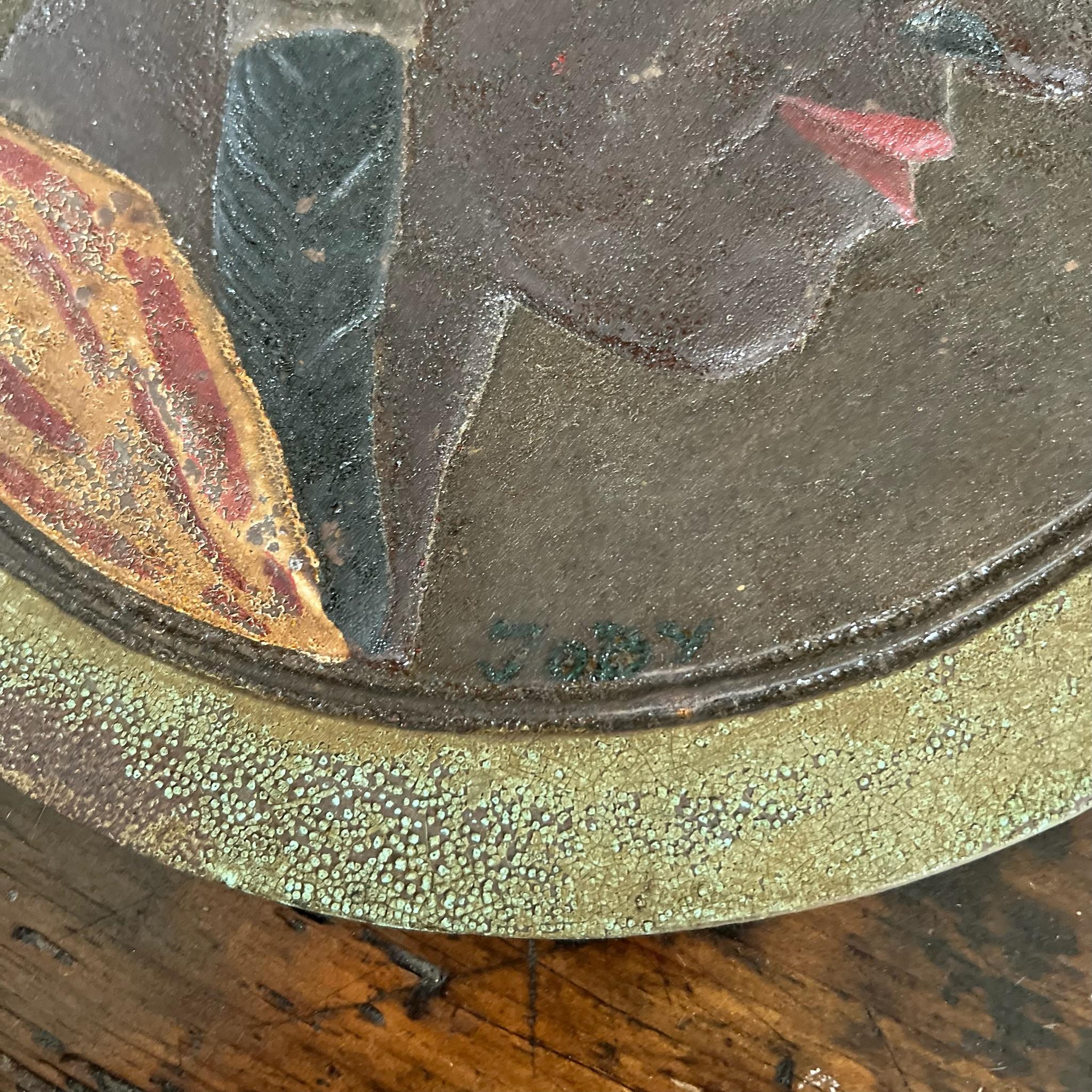 Plaque en relief en fonte des années 1920, puissante et bien rendue, représentant un Amérindien de profil, avec sa peinture multicolore d'origine et sa coiffe de plumes éclatantes. Cette lourde plaque circulaire de style médaillon était probablement