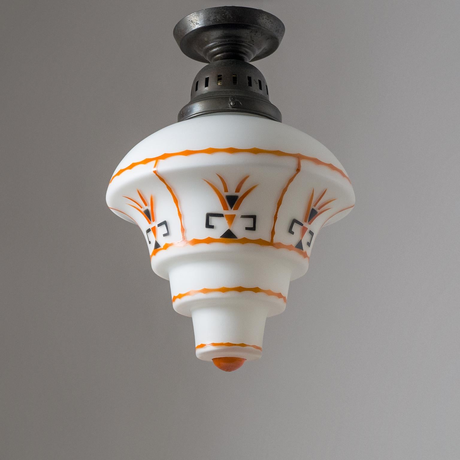 Rare Art Deco ceiling light, early 20th century. Dark patinated brass hardware with a cased glass diffuser which is enameled with an orange and black abstract decor. Very nice original condition with patina on the brass. One original brass and
