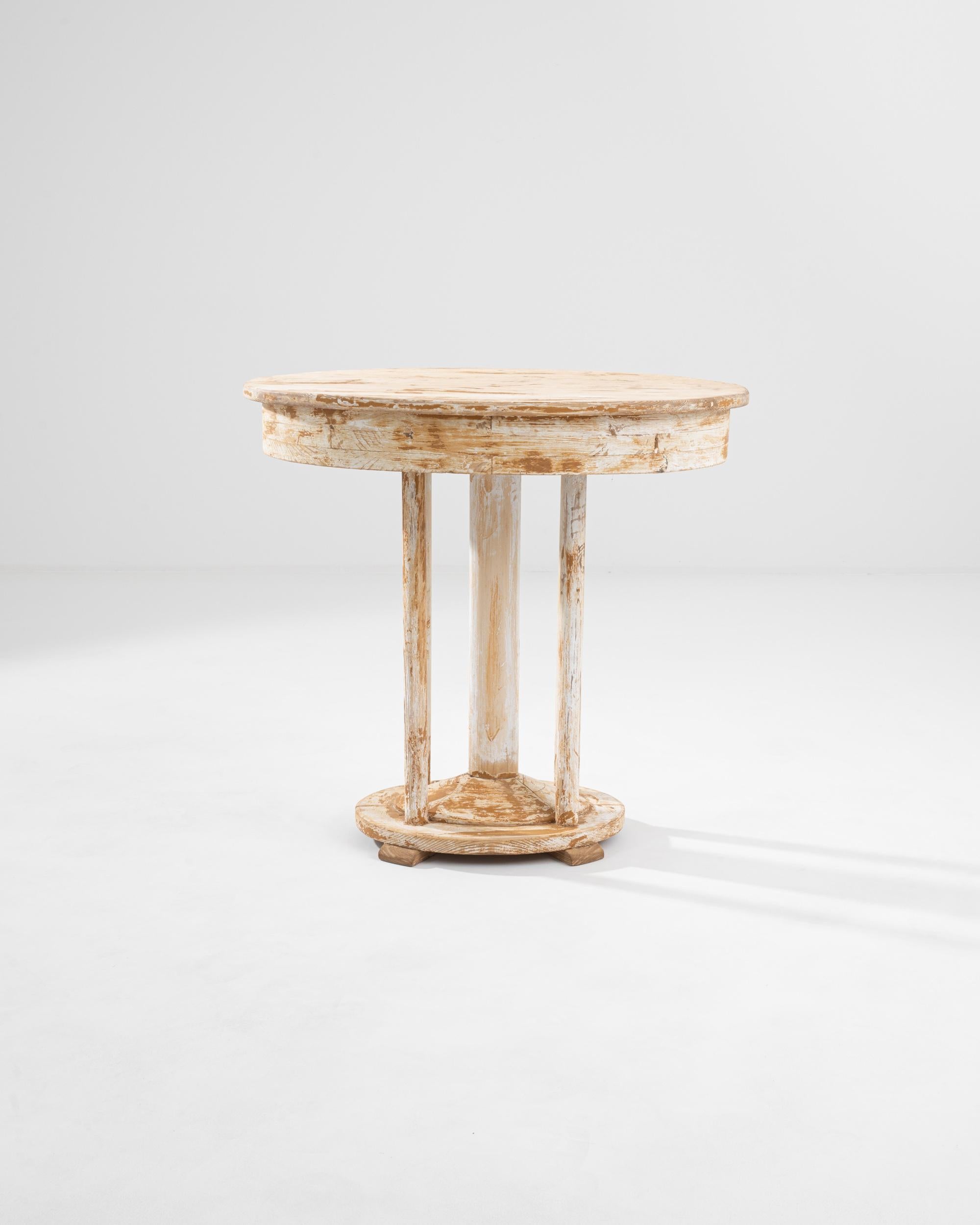 Balancing elegant simplicity with timeworn charm, this wooden side table offers a unique vintage accent. Made in Central Europe in the 1920s, the form evokes the bold shapes of Art Deco, while the distressed patina of the painted surface lends a