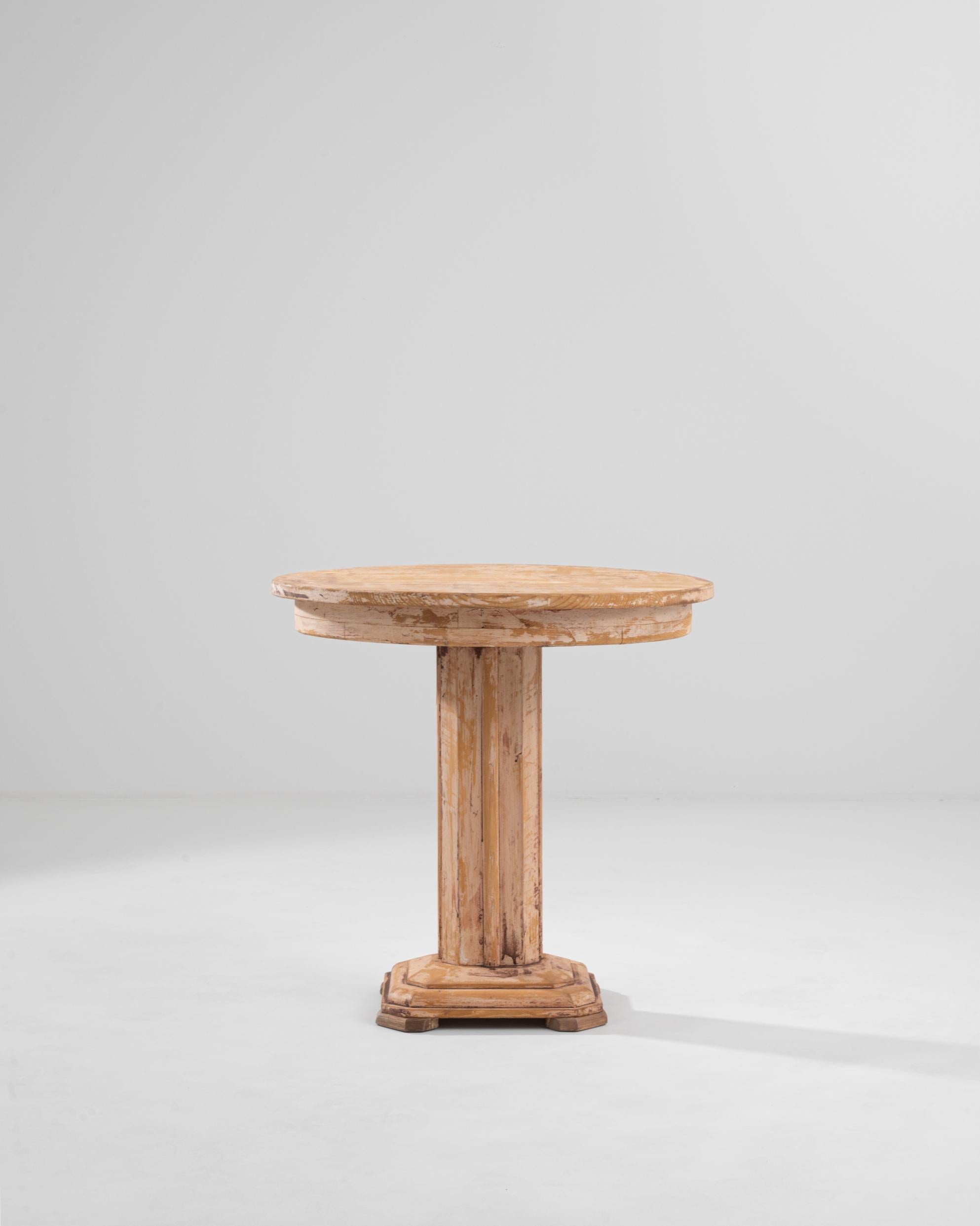 Made in Central Europe in the 1920s, this vintage wooden side table combines a graceful silhouette with a unique patina. The stripped-back simplicity of the design has an inherent elegance and equilibrium: a round tabletop rests atop a central