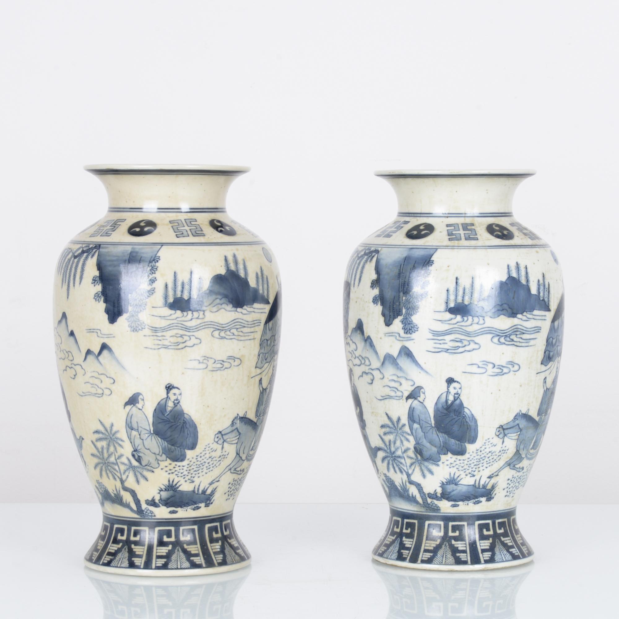 A pair of matching 33 cm blue and white painted vases, produced in China circa 1920. With a scene of the end of a pilgrimage, this harmonious set of aged porcelain vases imbue a sense of peace wherever they’re placed.