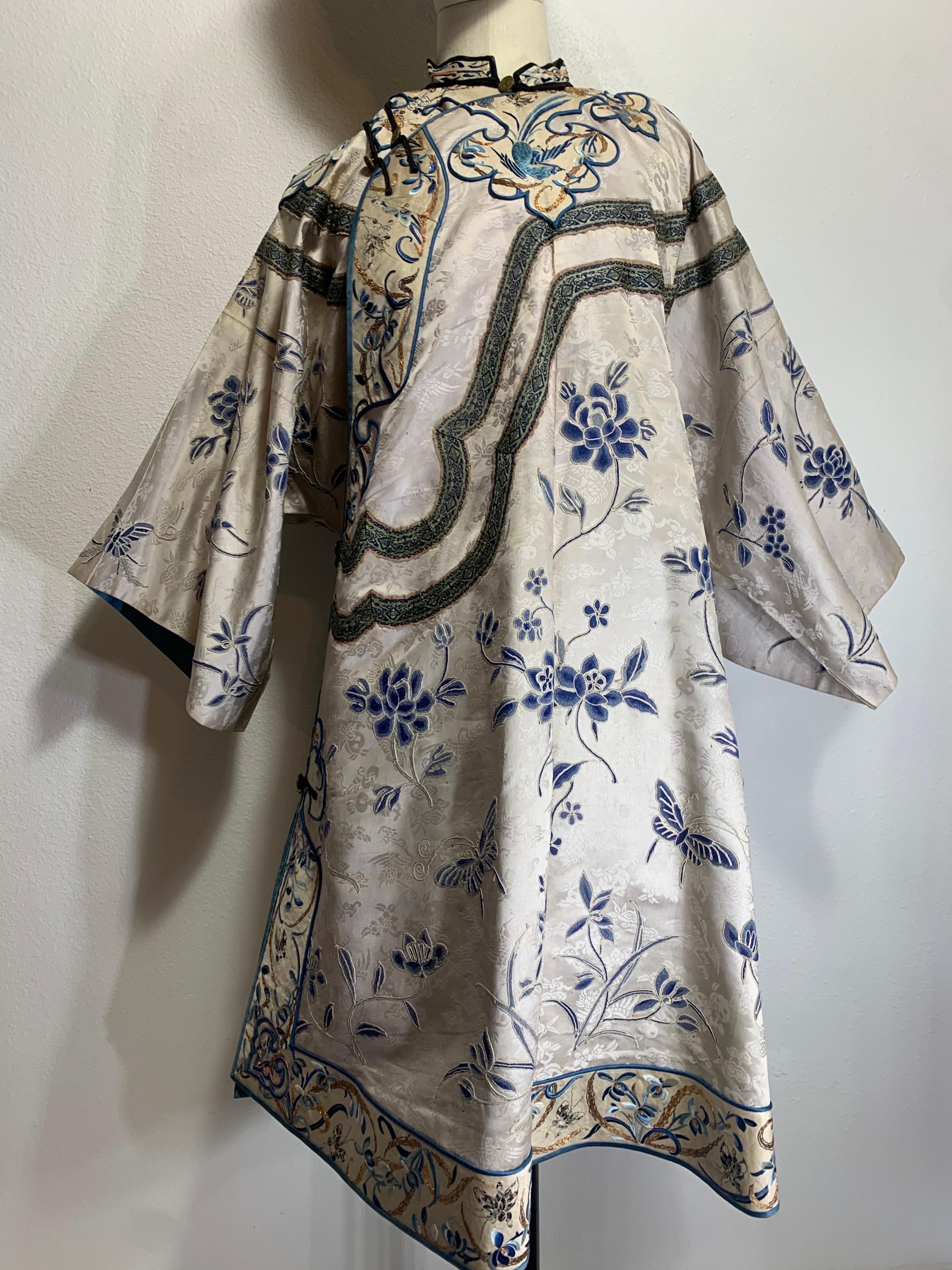 1920s Chinese Traditional Embroidered Side-Closure Silk Summer Coat in Blues and Porcelain White:  Asymmetrical closing with decorative Chinese floral and butterfly motifs in gold thread embroidery and applied ribbon. Lined in blue silk. Bronze coin