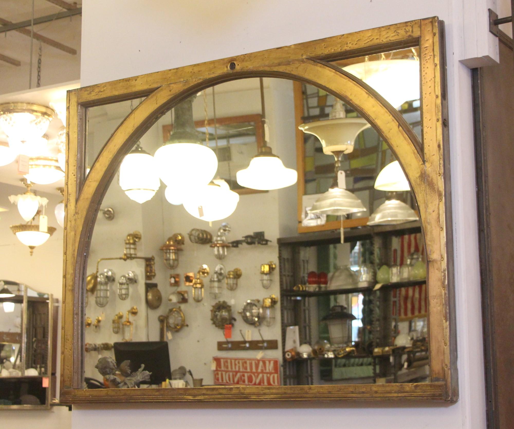 Mirror made from a 1920s copper clad window with an arched center. This window was sourced from an early 20th Century NYC building. Early 20th Century skyscraper windows often were clad with brass or copper as both a weather and fire proofing. This