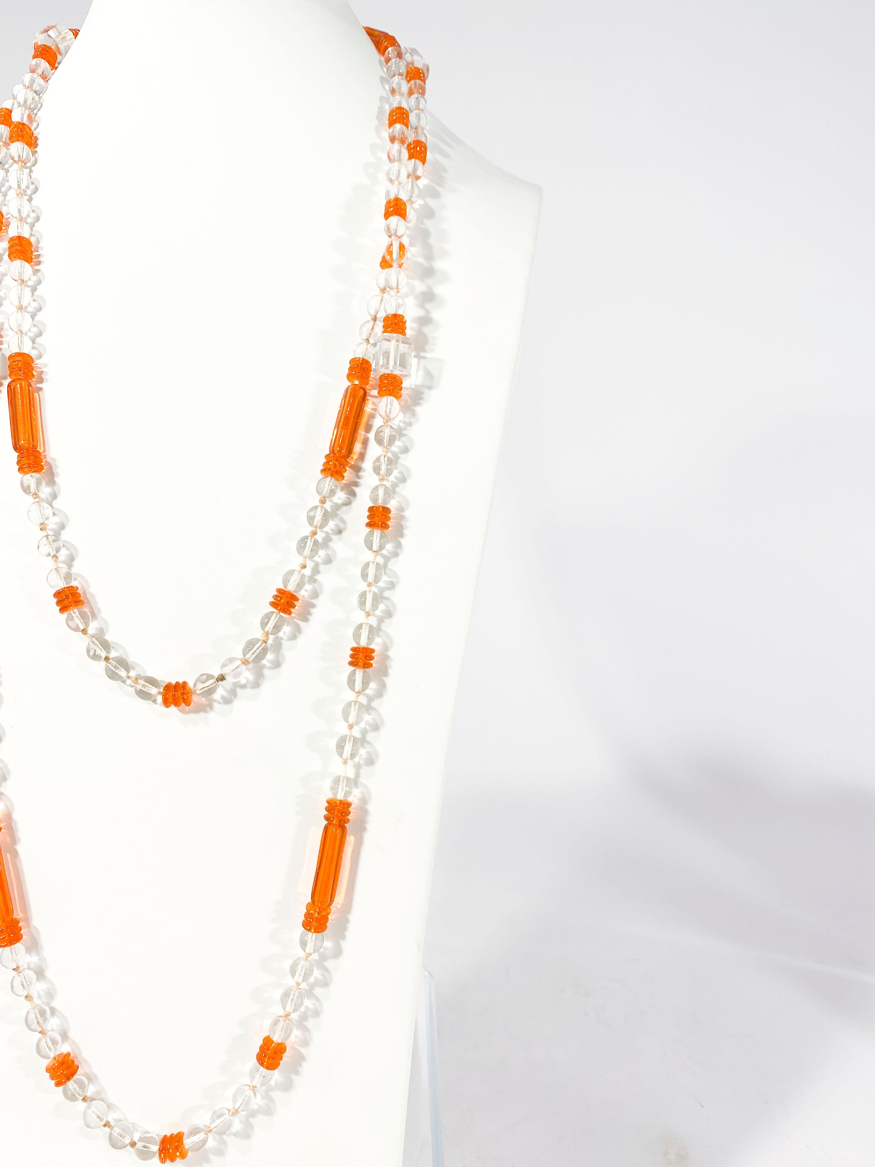 1920s Art Deco extra long Flapper-style beaded necklace. This single strand of beads features clear crystal beads with orange art glass evenly distributed thought the strand. 