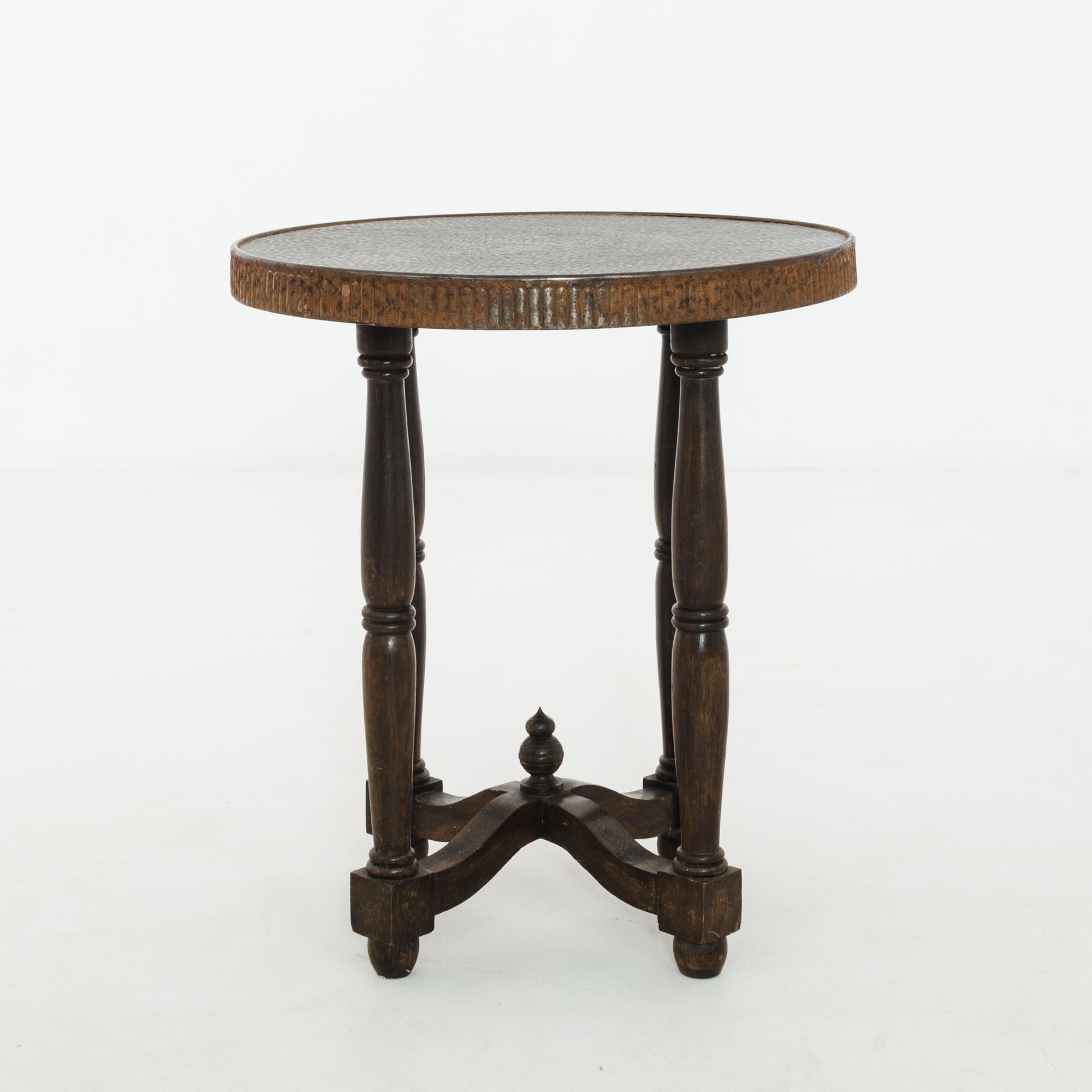 A wooden round table with metal top from Czechia, produced circa 1920. A small round side table with arched x stretcher capped by a two-tier finial in the style of the famous domes from the St. Basil’s Cathedral in Moscow. The embossed metal top has