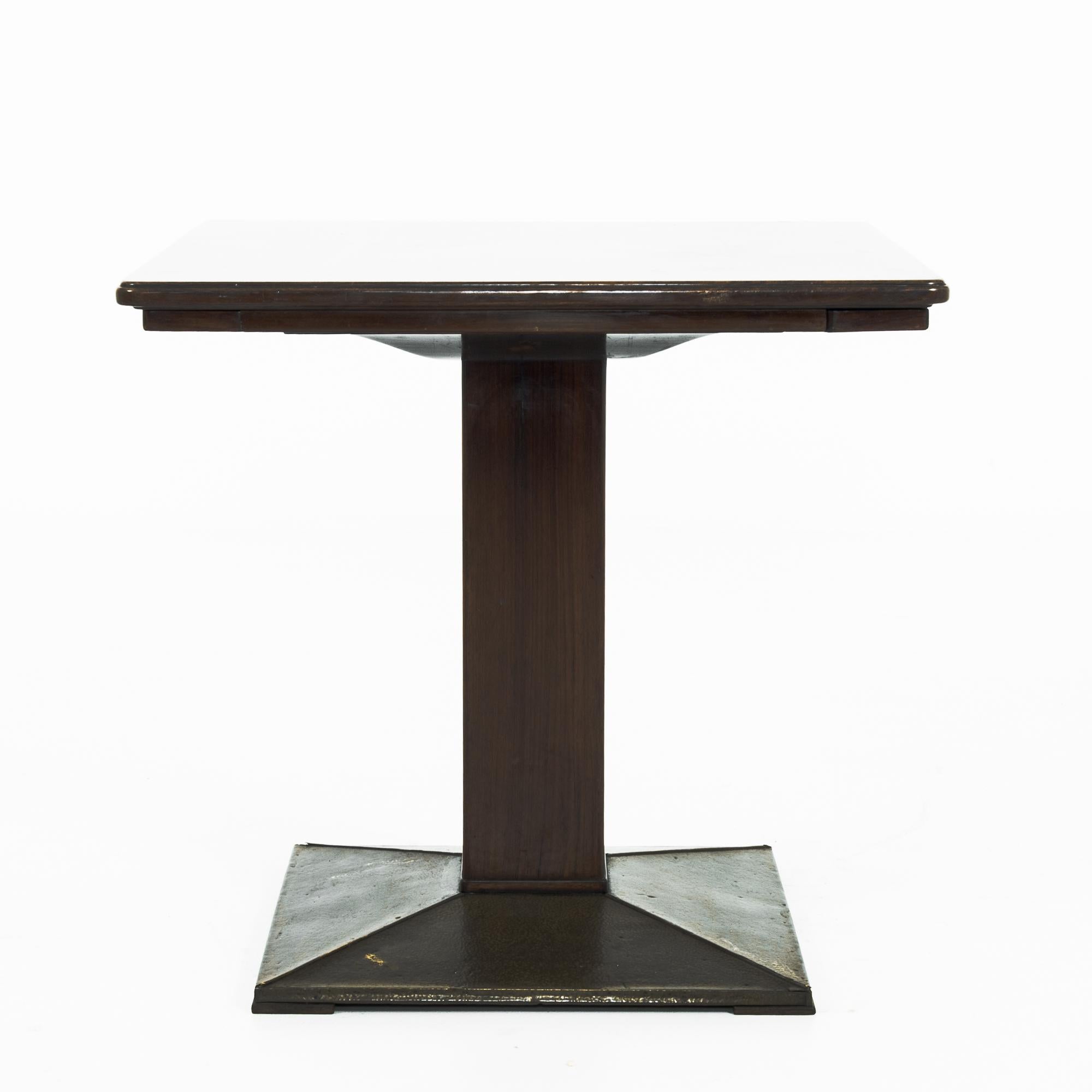 Sleek lines and sliding brass drink holders give this 1920s table a sense of Modernist luxury. Made in Czechia, a square pillar atop a metal base supports a tabletop of polished wood. Wooden drinks holders, inlaid with brass, fan out from underneath