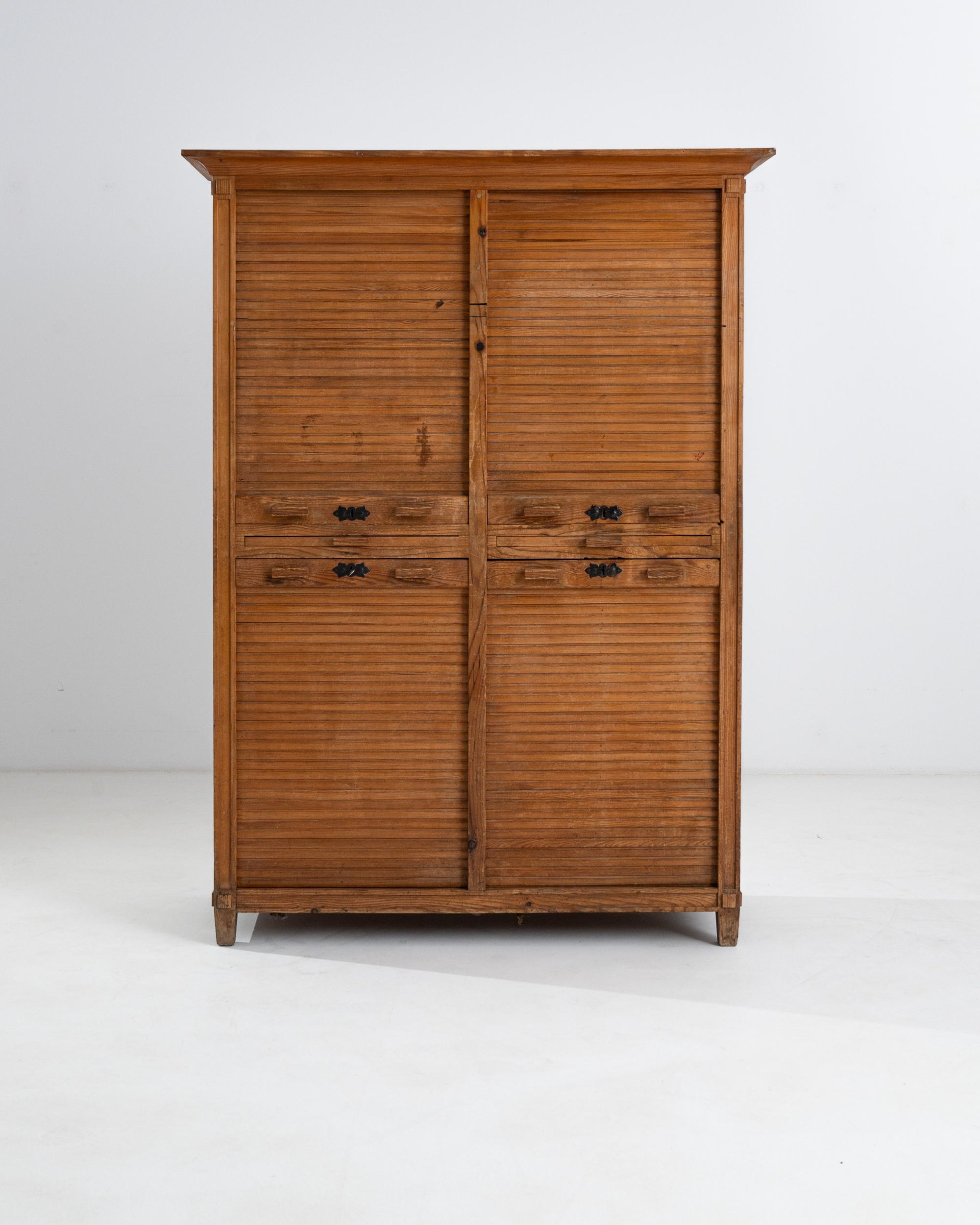 This beautiful 1920s cabinet epitomizes the elegance and innovation of Central European carpentry. Sourced from Czechia, vertical roller blinds serve as cupboard doors, retracting gracefully into the cabinet to reveal a geometric arrangement of