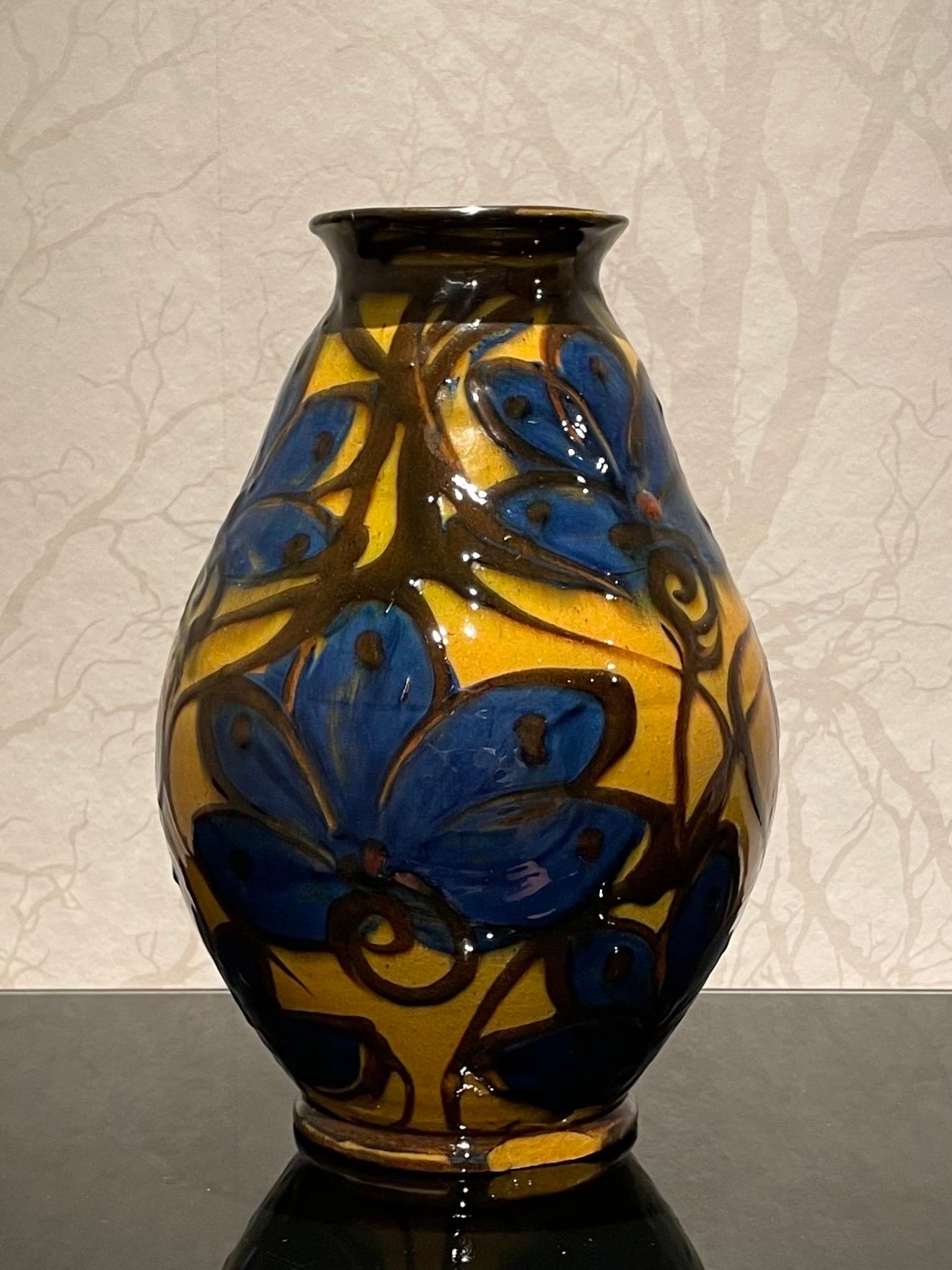This is the 1920s Danish 27 cm high ceramic vase by Herman Kähler. 

This vase comes with a baluster shaped body, high glossy surface and deep brown and blue colors on a base of a mustard yellow uranium glaze. 
It has a beautiful cow horn glazed