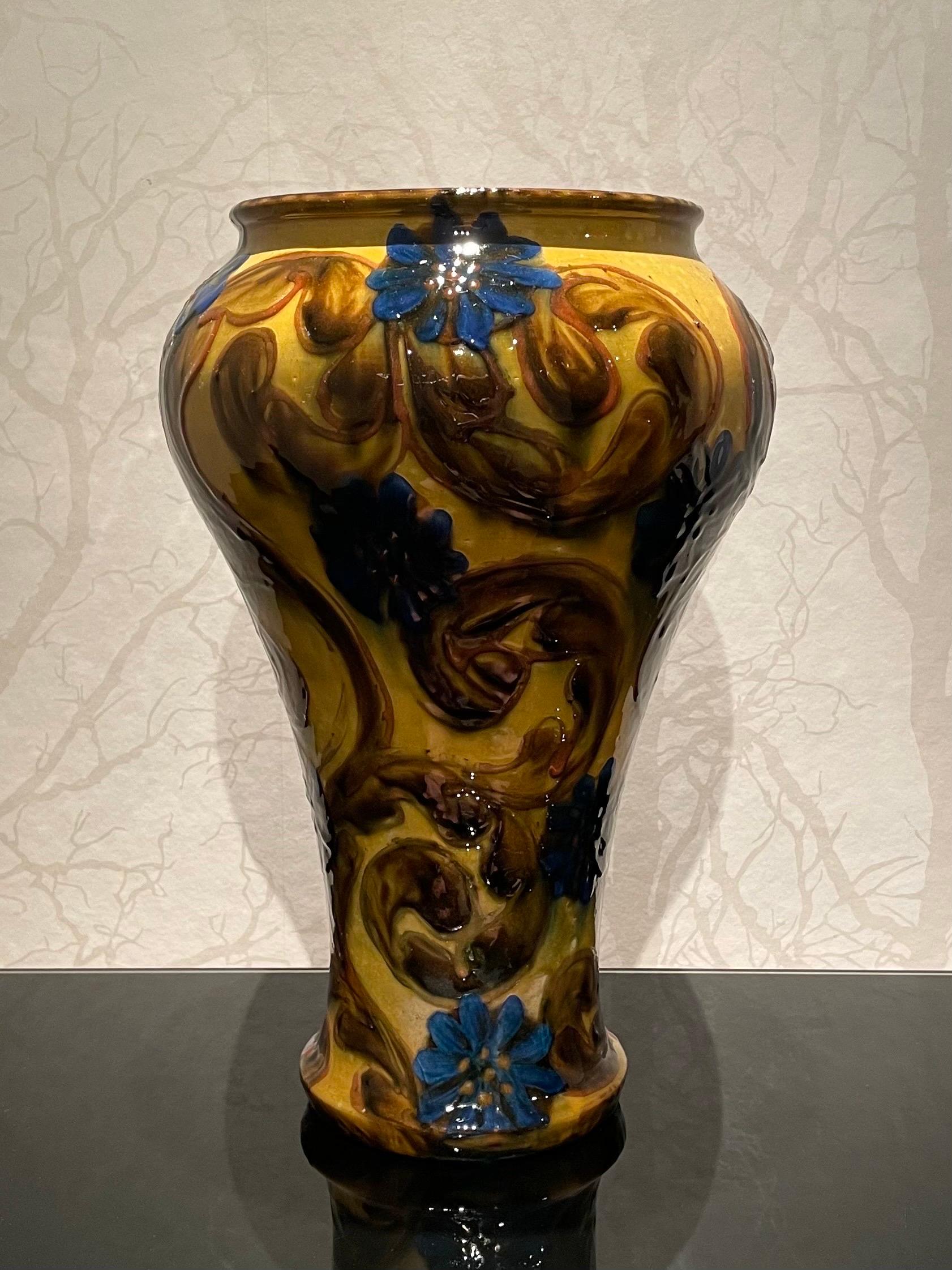This is the 1920s Danish 36 cm high ceramic vase by Herman Kähler.

This vase comes with a tall, sturdy and proud shaped body, high glossy surface and brown and blue colors on a base of a mustard yellow uranium glaze.
It has a beautiful cow horn