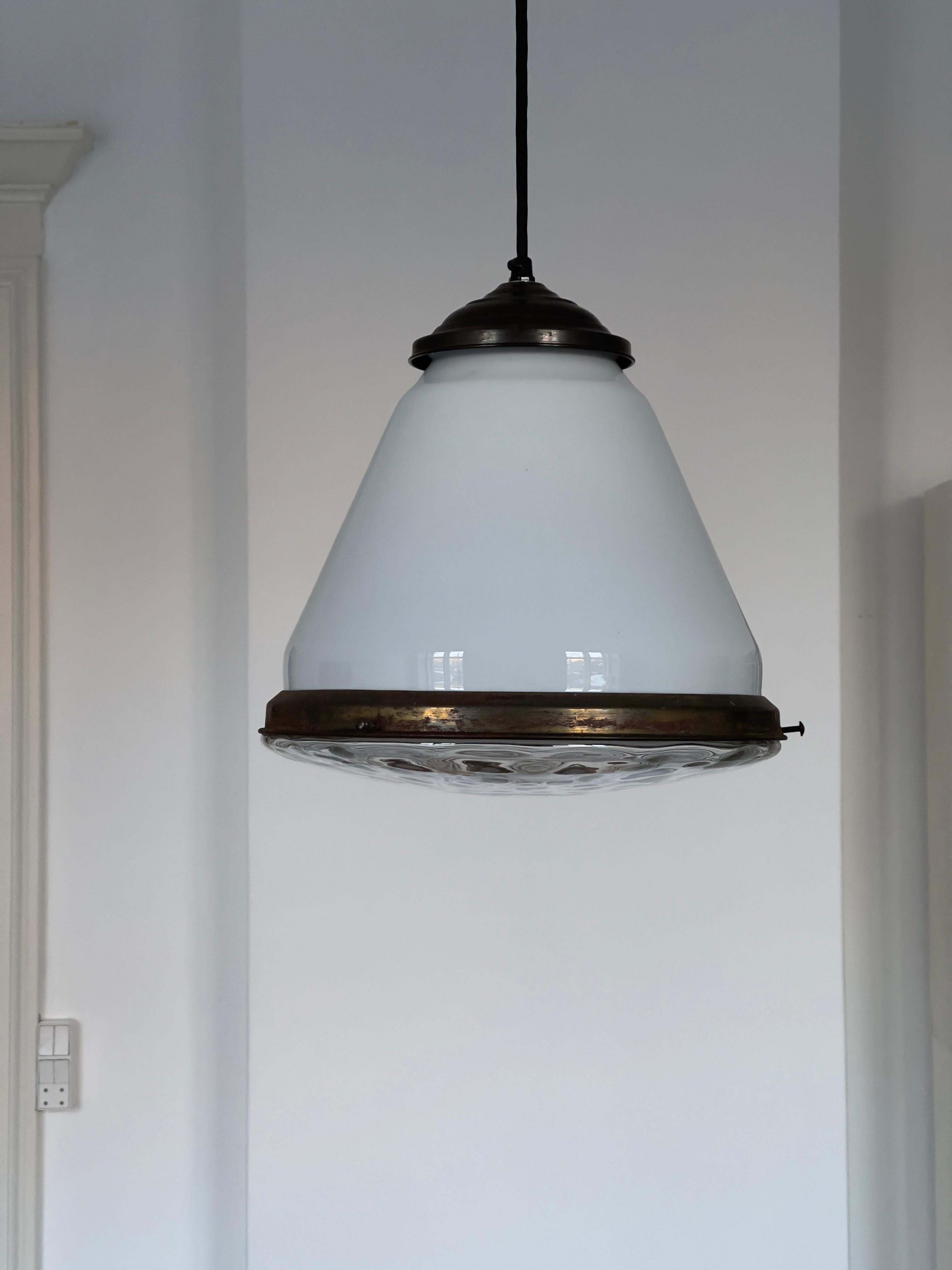 Elegant danish pendant / chandelier in a beautiful combination of white opaline conical glass with a raw glass bottom and patinated brass fittings. The pendant is in a rare good condition.