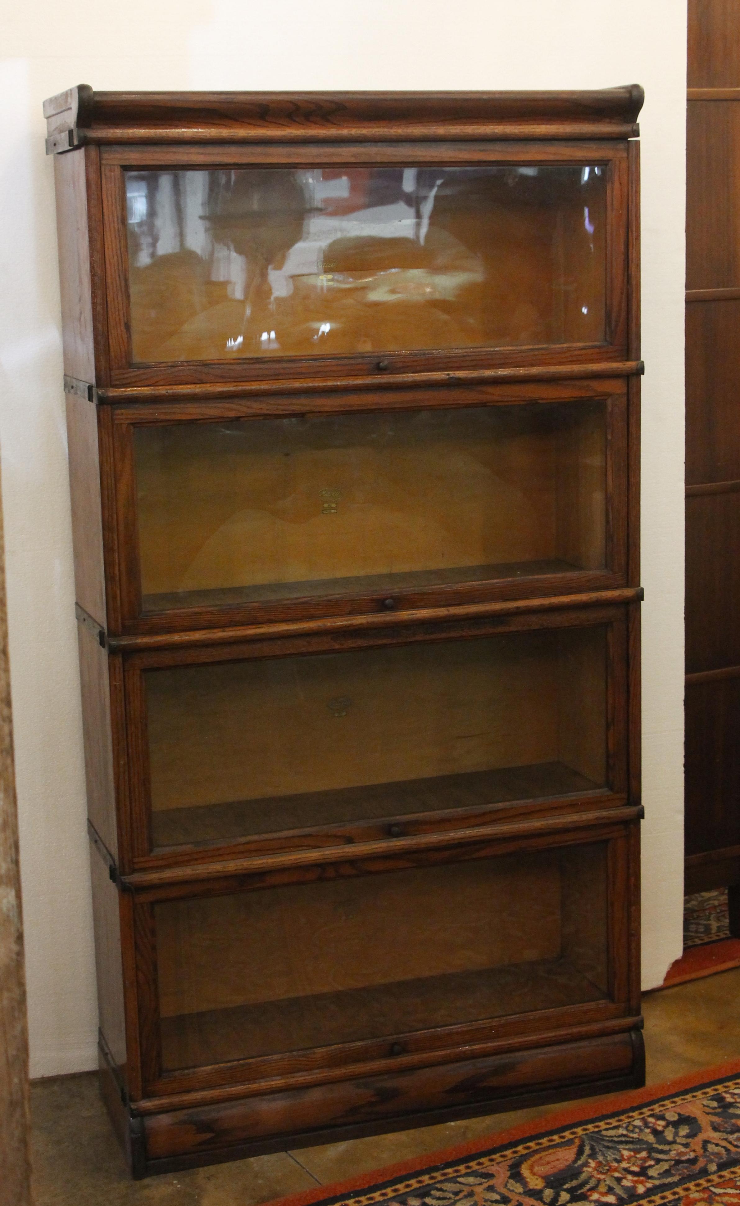 1920s dark wood tone barrister bookcase with four pullout / pull-out glass doors. Made by Macey. Stamped 