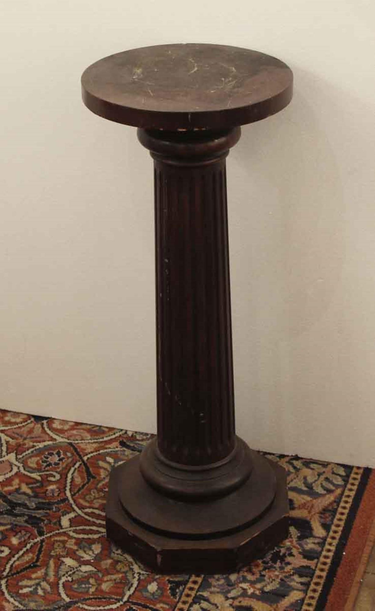 1920s dark wood tone pedestal with a round top. There is some wear in the wood from age and use. This can be seen at our 2420 Broadway location on the upper west side in Manhattan.