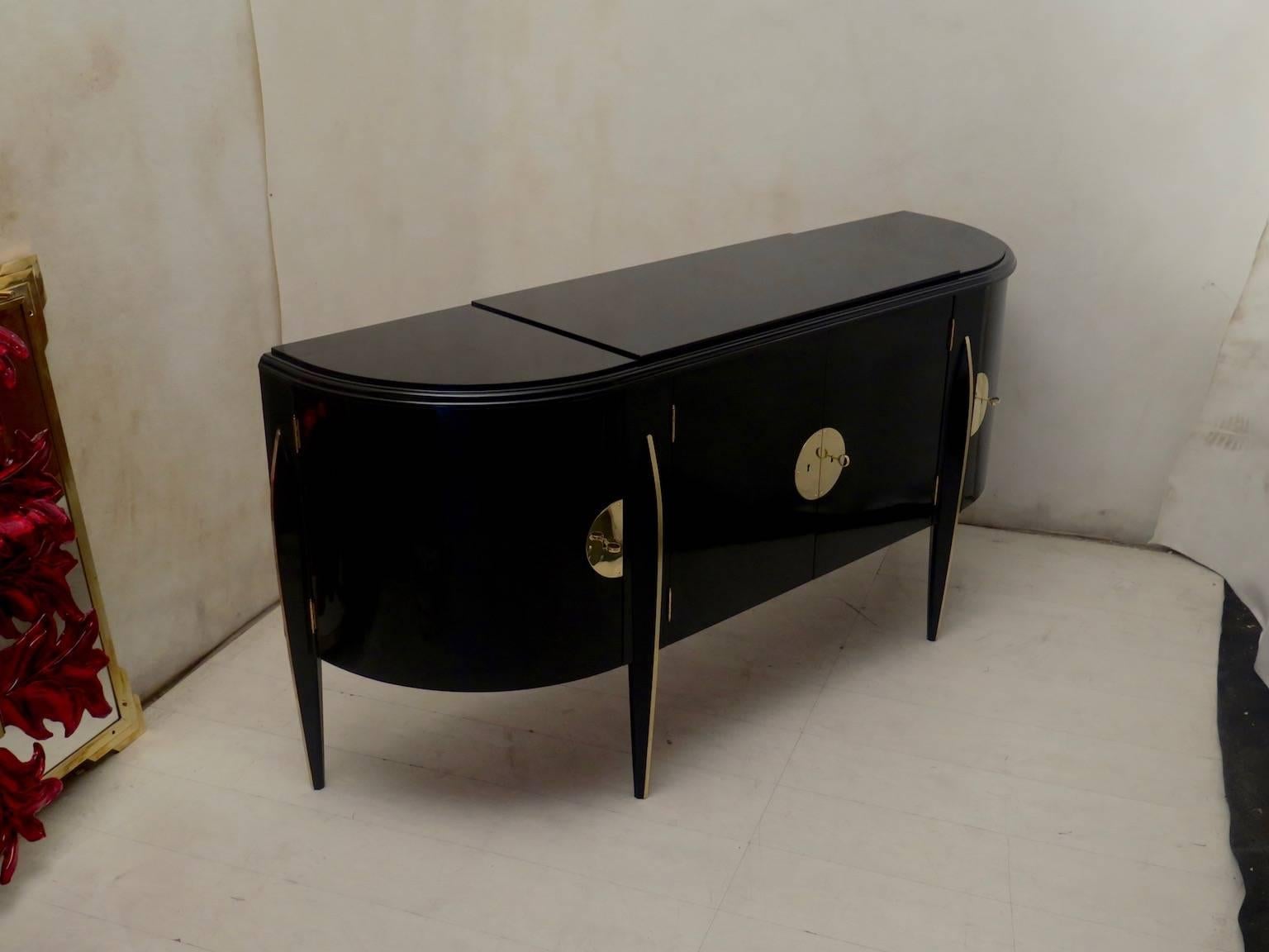 Italian Art Deco sideboard all polished in black lacquer with special brass inserts. The sideboard has the shape of a half moon, with four doors, two-curved lateral and two central straight coupled. The legs are two lateral at the end of the