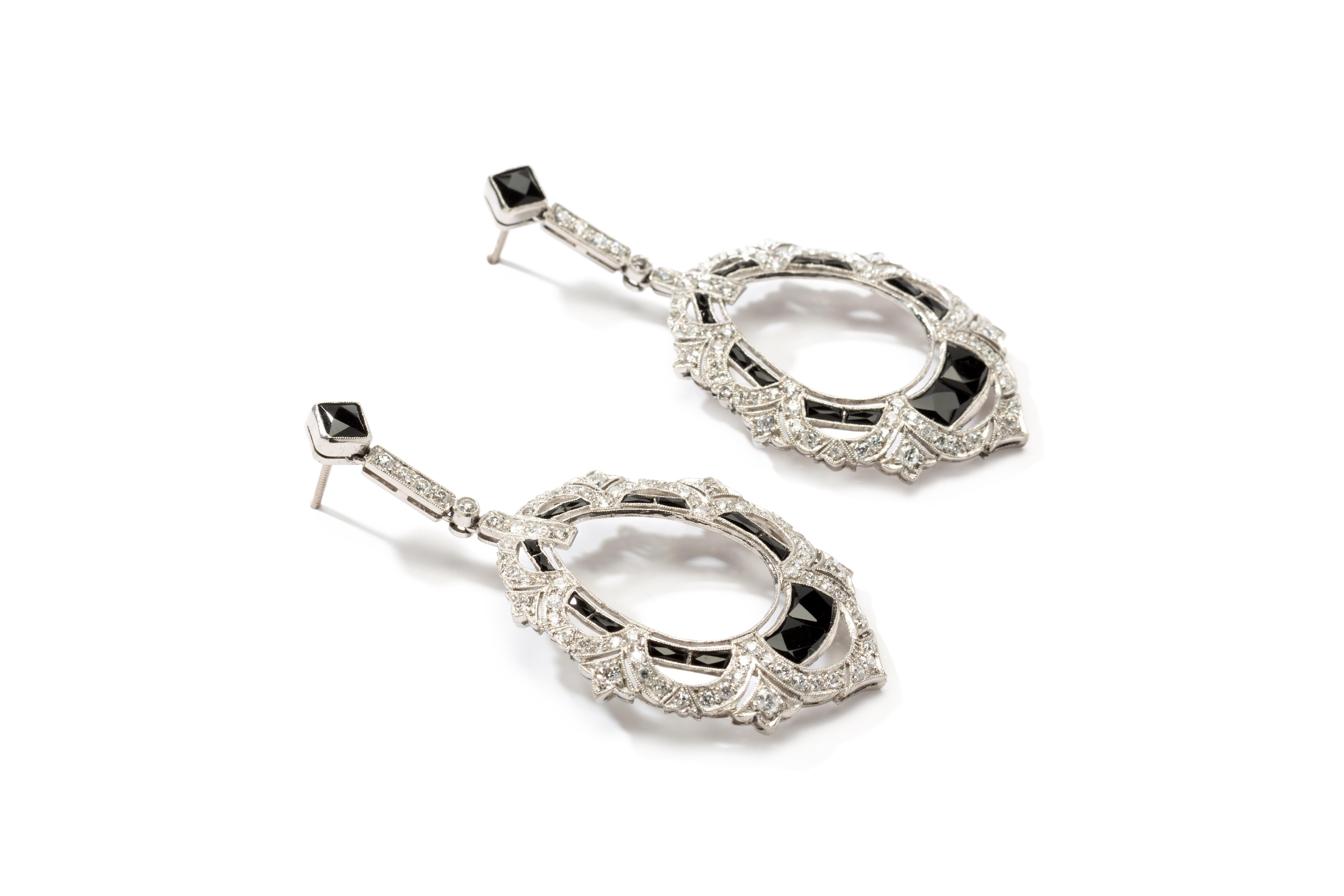 Pair of platinum openwork dangle earrings with 196 old-mine-cut diamonds ( ca. 5,3 carats ) and 30 onyx. Measurements: Length: 2.28 in ( 5,8 cm ), Width: 0.87 in ( 2,2 cm )
