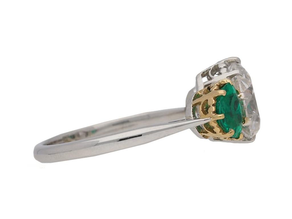 Drop shape old mine diamond and emerald ring. Set to the centre with a drop shape old mine diamond weighing 1.56 carats, VS1 clarity, G colour, flanked by two heart shape old cut Muzo mine Colombian emeralds with an approximate combined weight of