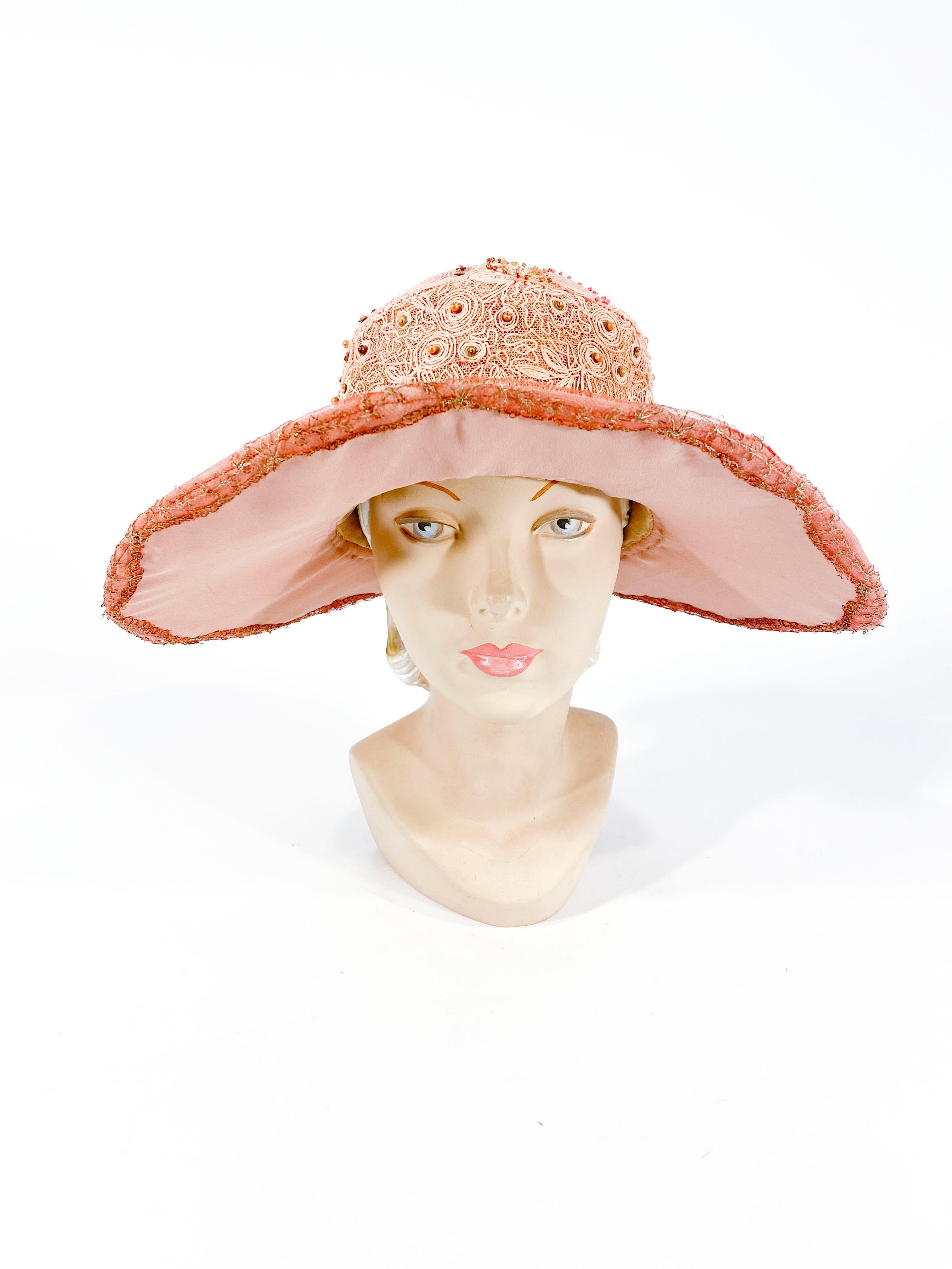 1920s Art Deco dusty rose pink picture hat with wide brim that is covered in silver lamé confided in a floral patter. The deep crown is covered in a pale pink soutache embroidery with glass beads and pears. The hat band is adorned with handmade silk
