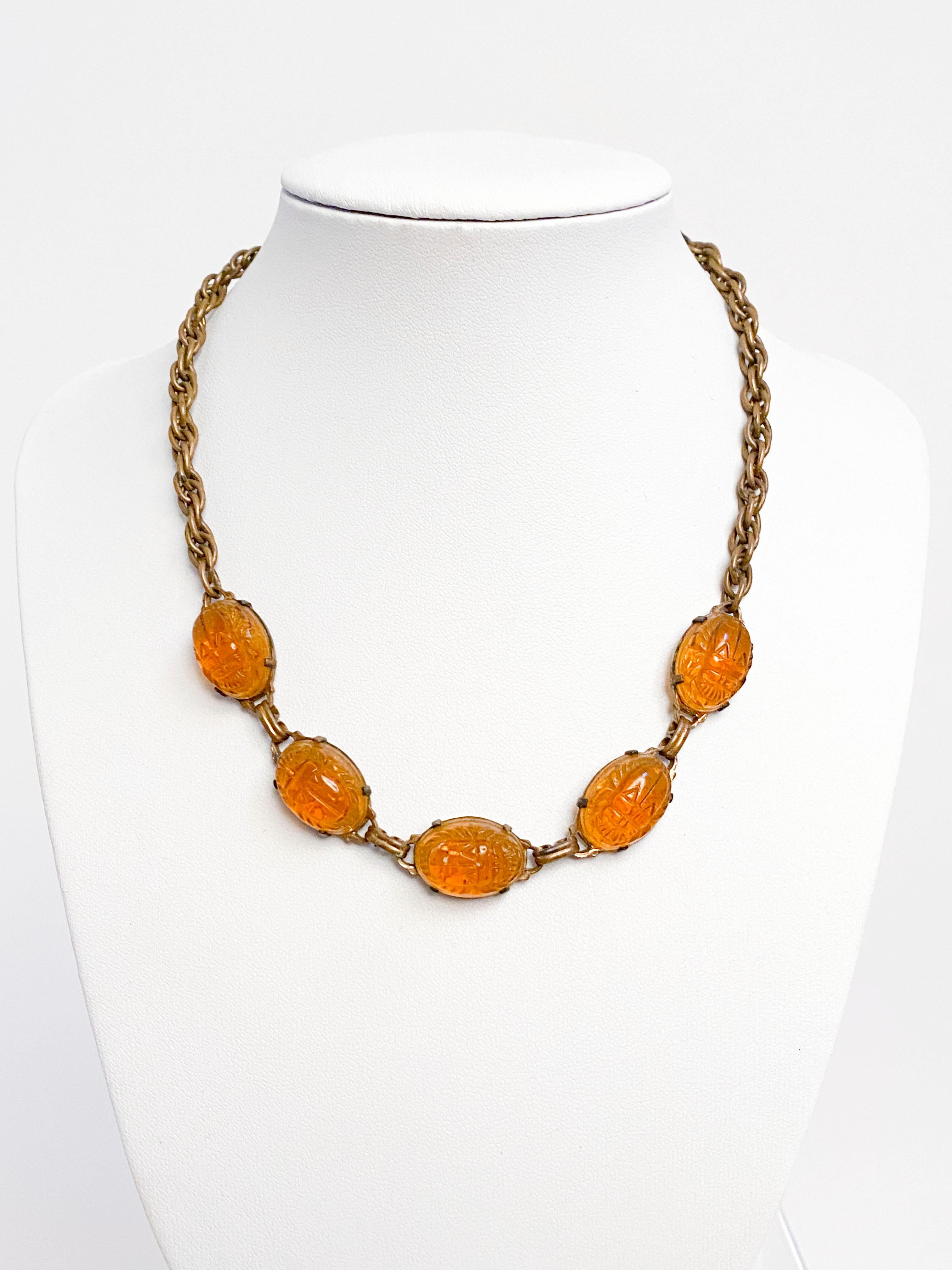 1920s Art deco Egyptian Revival brass necklace featuring five amber-colored scarab beetle art glass pieces. 