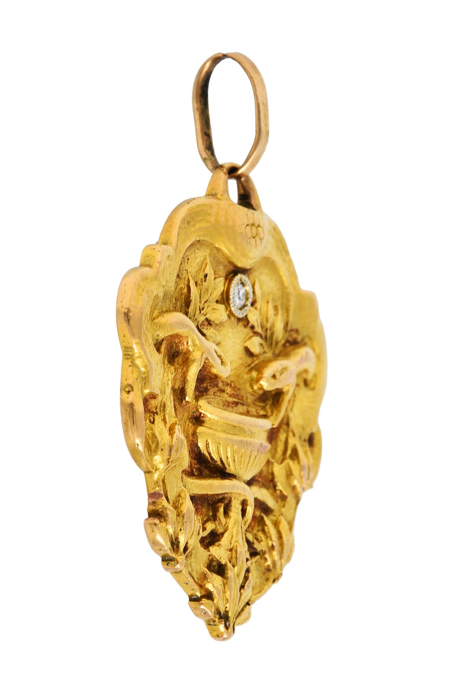 Pendant charm is designed as two intertwined asp snakes hovering over a goblet

Alluding to Cleopatra's romanticized death

Surrounded by stylized foliate and accented by 0.03 carat single cut diamond

Back is emblazoned with a dated