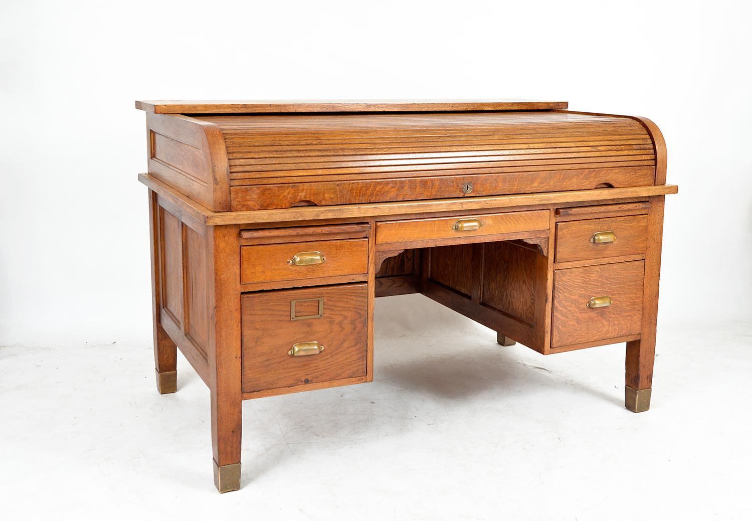 A good example of a 1920s roll top desk in a lovely honey-coloured quarter-sawn oak. It’s a very elegant piece standing on four brass-capped feet, giving it an airy sophistication. 
The tambour rolls back into the desk to reveal a smooth desktop,