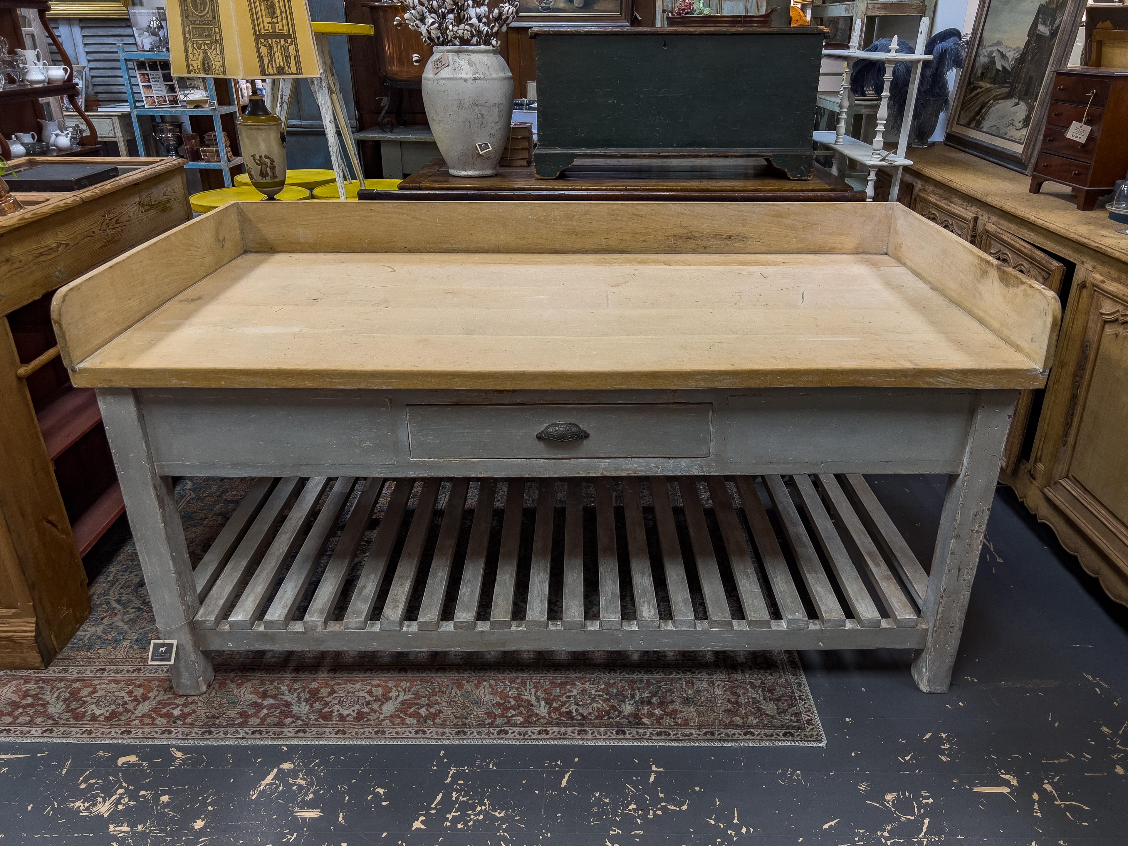 1920s English Baker’s table with Sycamore top. The work surface is large and has a natural wood backsplash. The utilitarian base is painted, has a single drawer and a slatted lower shelf.