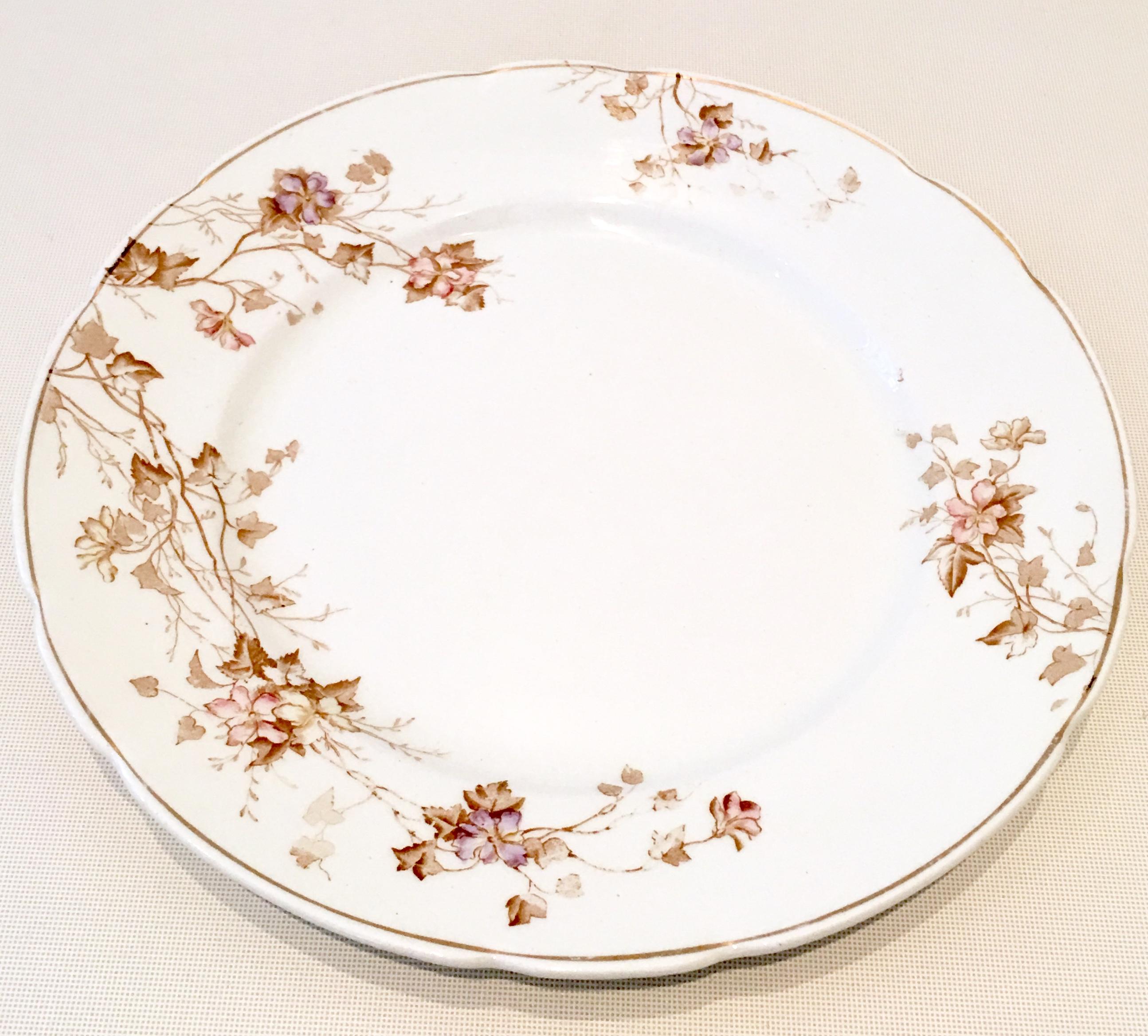 20th Century set of eight English ironstone dinner plates by Johnson Brothers. Pattern features a white ground, scalloped edge with 22-karat gold rim and brown with subtle lavender and pink floral vine motif. Each piece is marked on the underside,