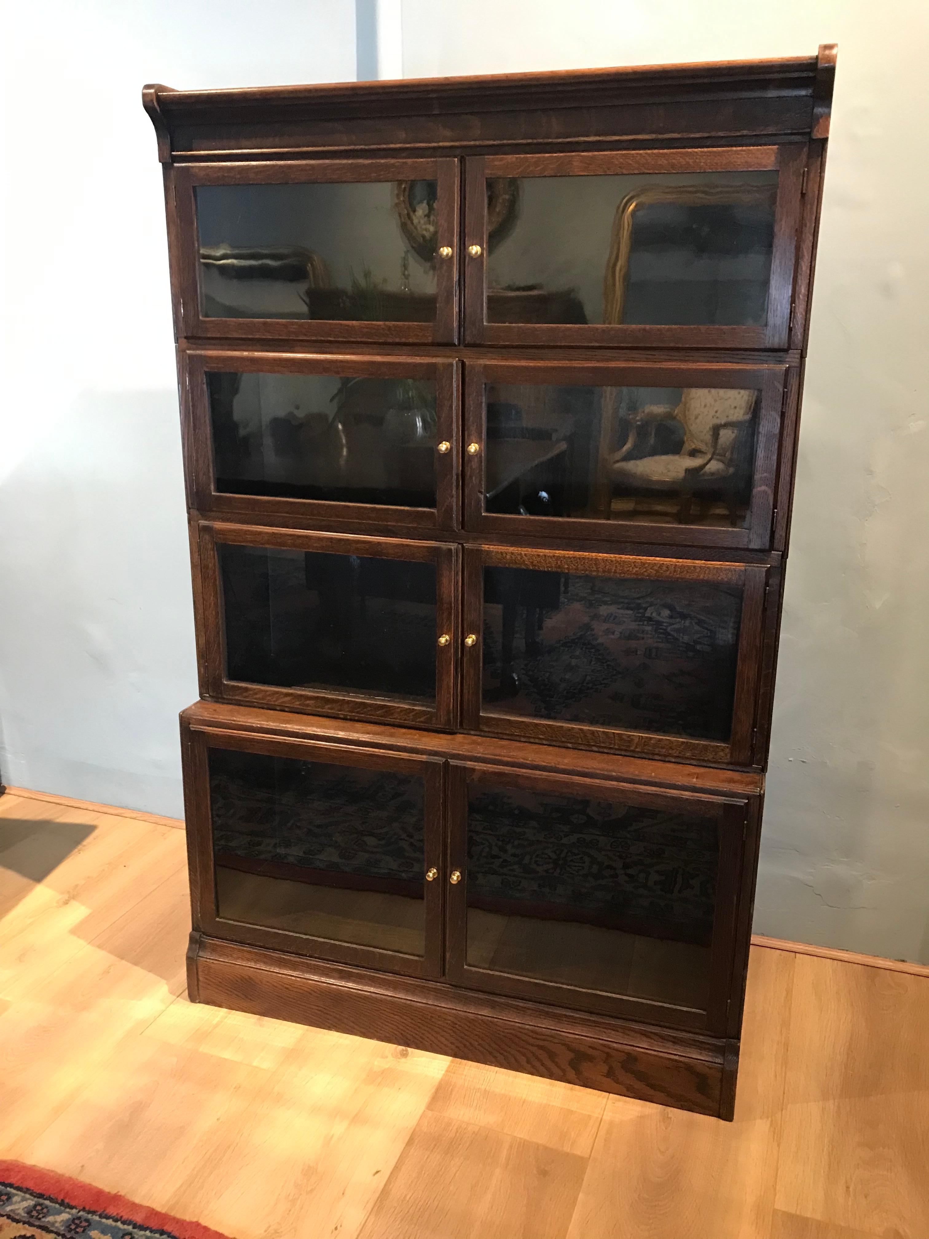 Oak Minty of Oxford style, modular, stacking, glazed bookcase in four sections.
Excellent condition with hand blown glass glazed doors and brass handles.
The lower base section is a depth of 30 cm graduating to a depth of 24 cm in the other three