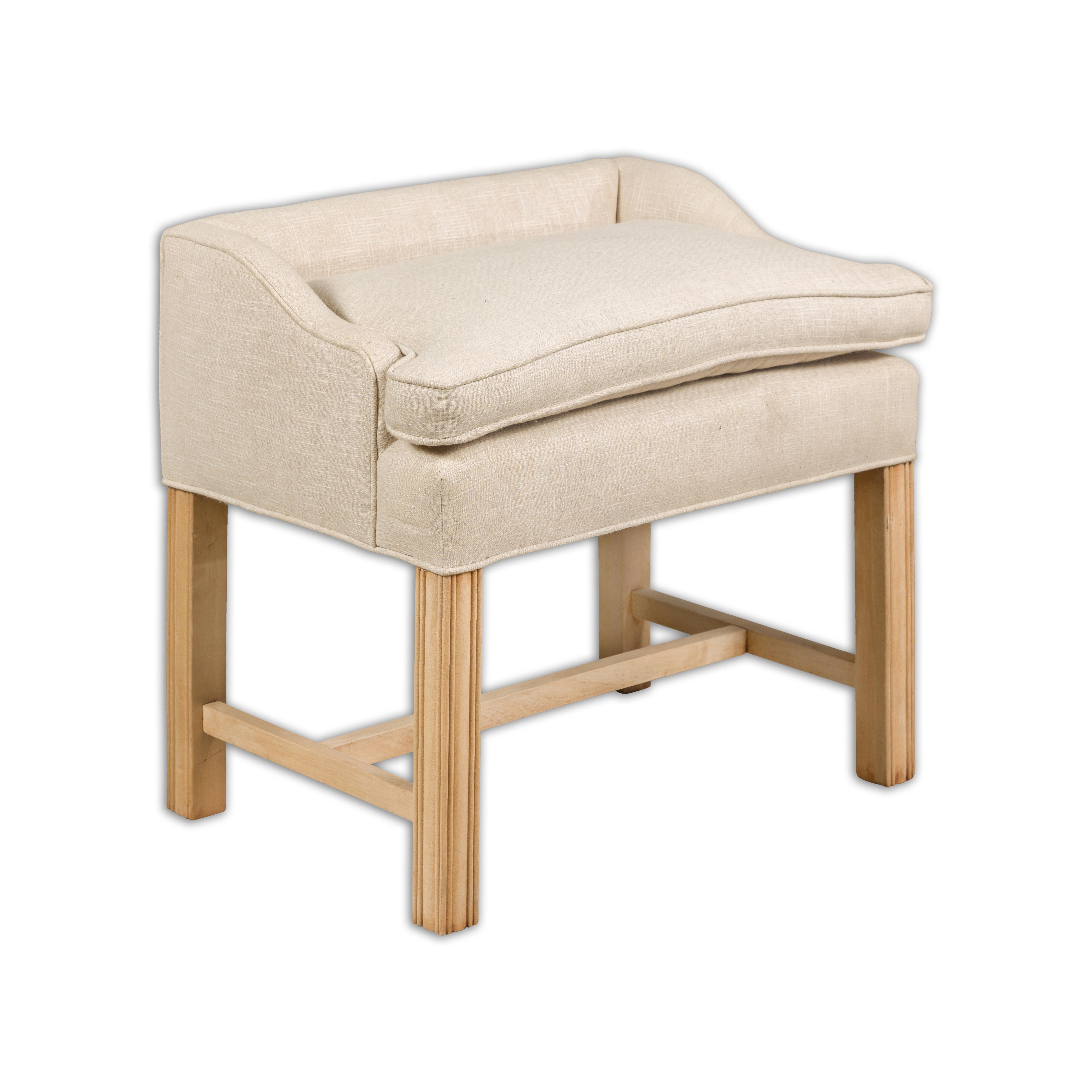 An English stool from circa 1920 with slightly raised back, straight carved legs, H-Form cross stretcher and newly reupholstered seat in linen. Introducing a distinguished English stool, dating from circa 1920, that seamlessly marries classic design