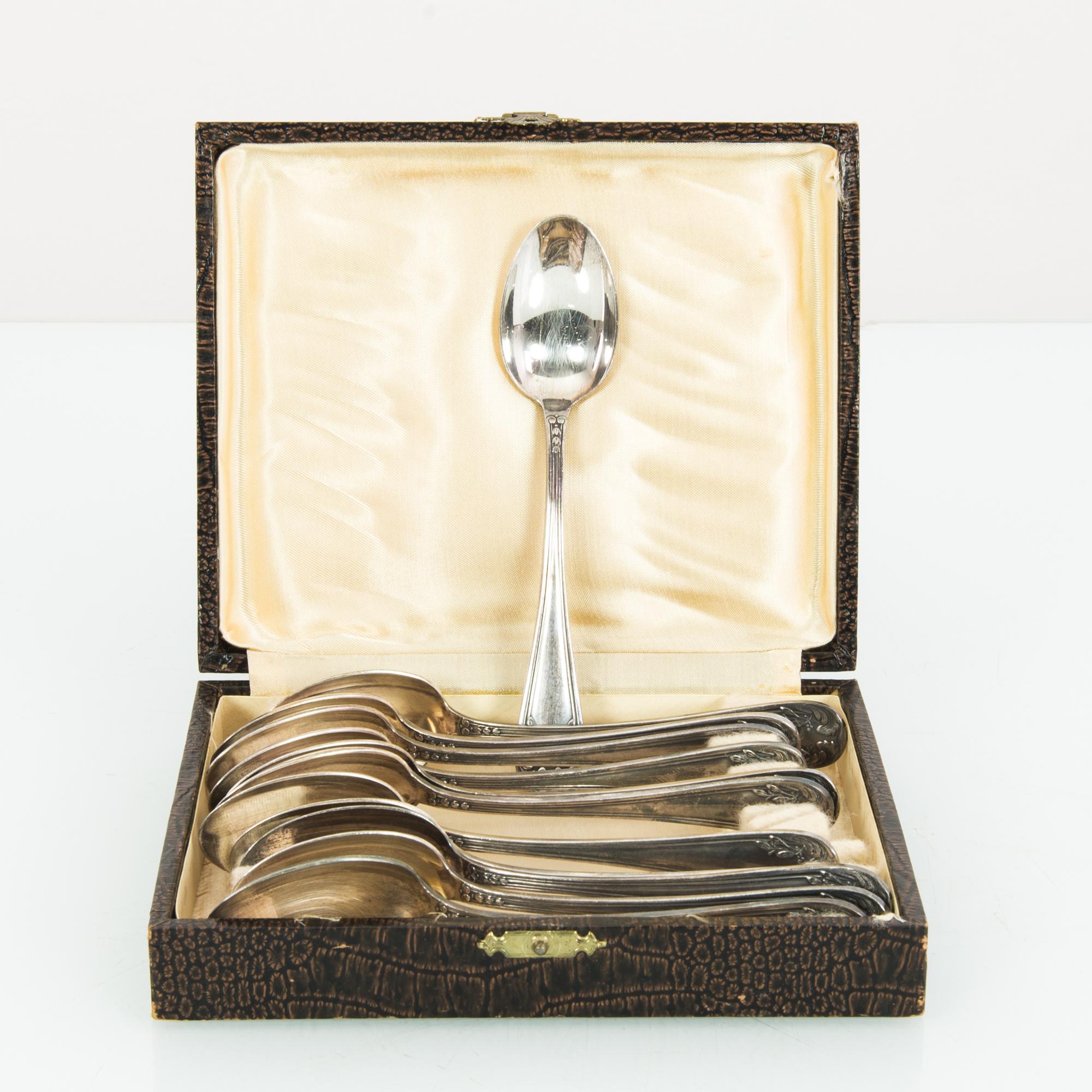 Made in Europe, circa 1920, this set of twelve silver-plated teaspoons features a bright, silvery sheen with decorative carvings on the handle. They can be stored or displayed in a hinged and lined box, accompanied with an aura of old-world