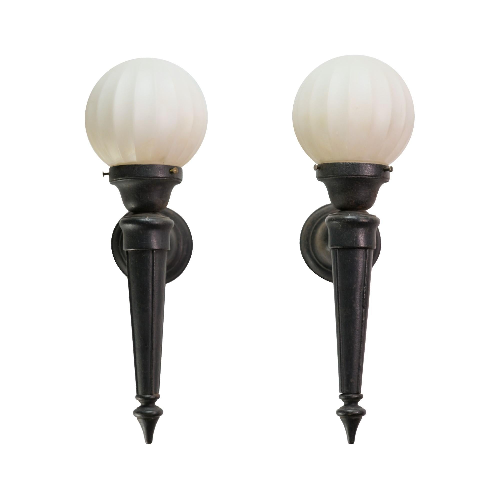 Antique pair of cast iron exterior sconces with fluted globe with frosted glass. These 1920's sconces are original and have a natural patina. Price includes restoration. Priced as a pair.