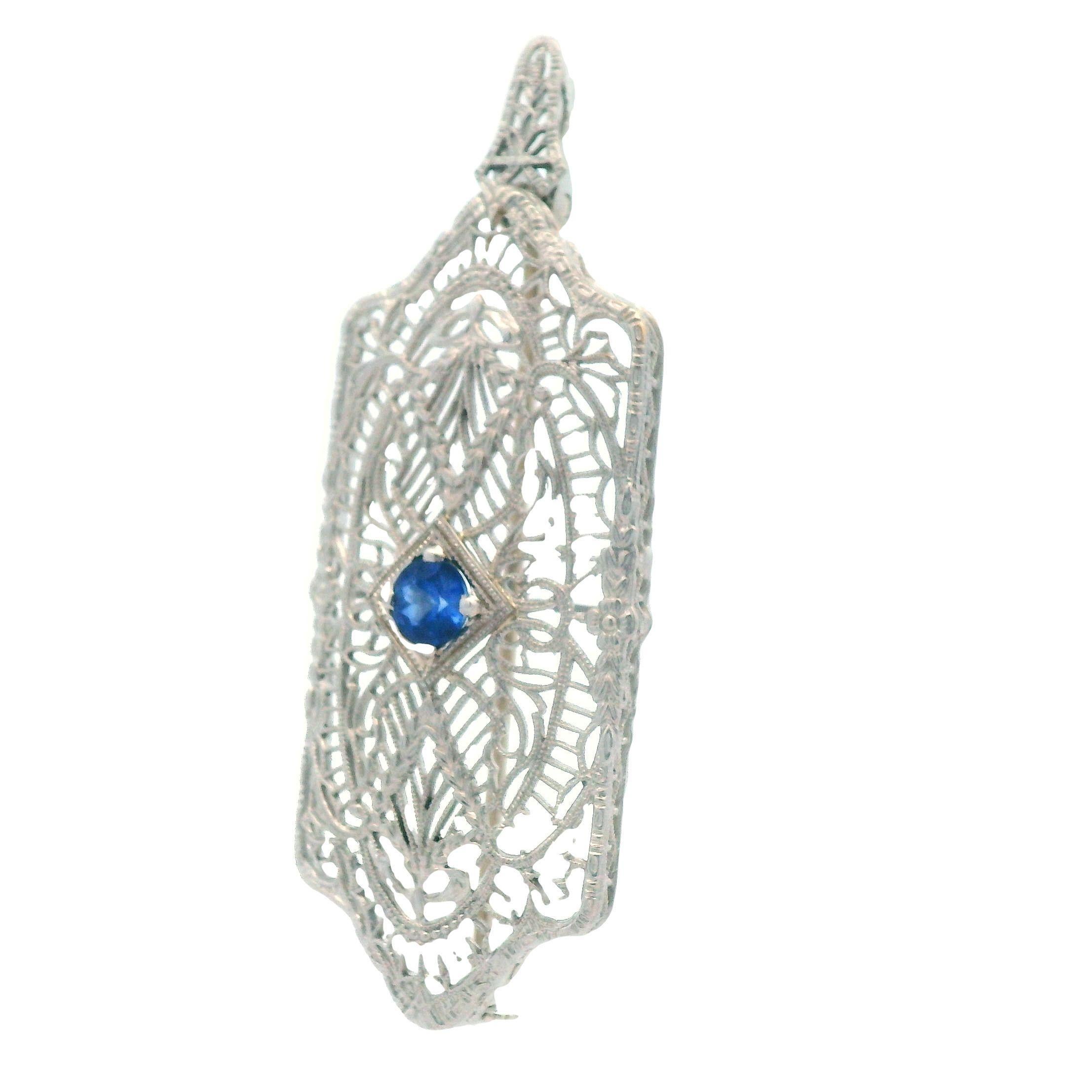 This enchanting filigree pin / pendant comes from the 1920's and is made with platinum over 14k white gold with a blue sapphire center stone. This pin can be worn in many different ways due to its option to be worn as either a pin or a pendant, as