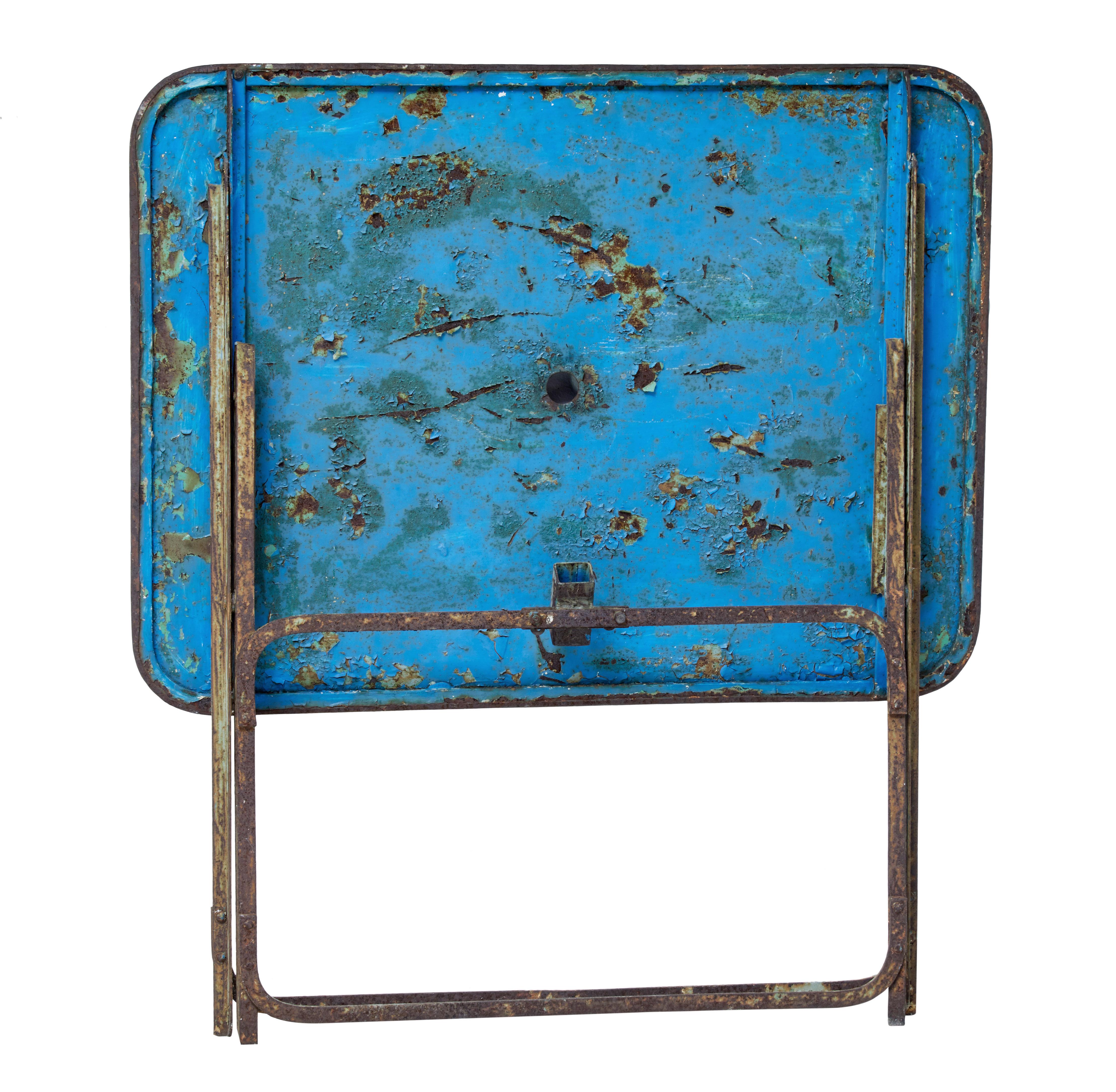 Good quality rectangular metal garden table from the 1920s.

Desirable bare rusted metal top with small parasol hole. Standing on folding base with traces of original paint.

Good example of a practical table for the garden or summer house. 
 