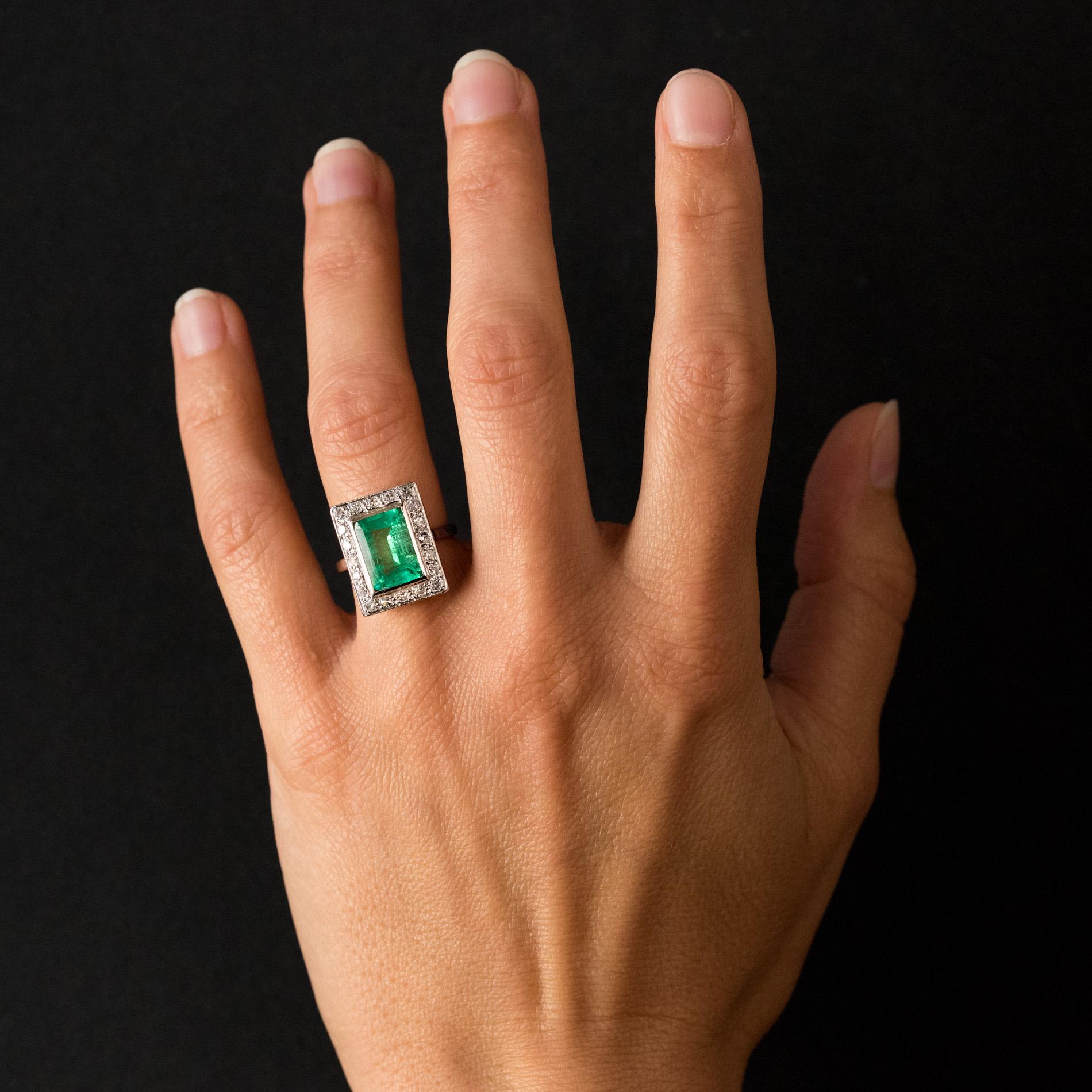 Ring in platinum and 18 karats white gold, eagle's head hallmark.
Rectangular, this beautiful authentic art deco ring is adorned, in closed setting, with a degrees-cut emerald, surrounded by diamonds. The basket is delicately perforated to let the