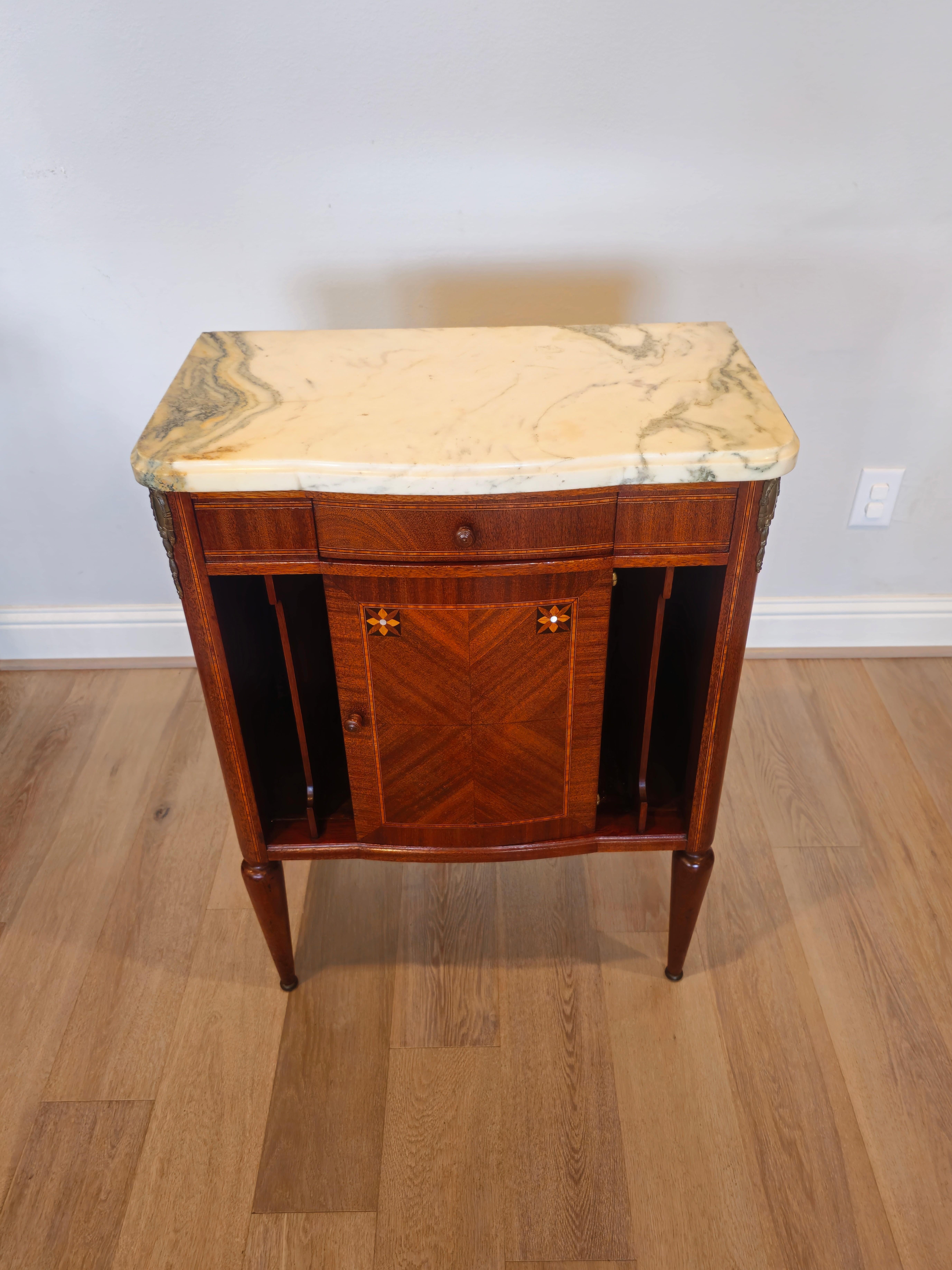 A lovely 1920s French Art Deco marble-top gilt bronze mounted mahogany inlaid nightstand.

Born in France in the early 20th century, crafted in elegant Louis XVI taste with luxurious period Art Deco influence, featuring stunning matched mahogany