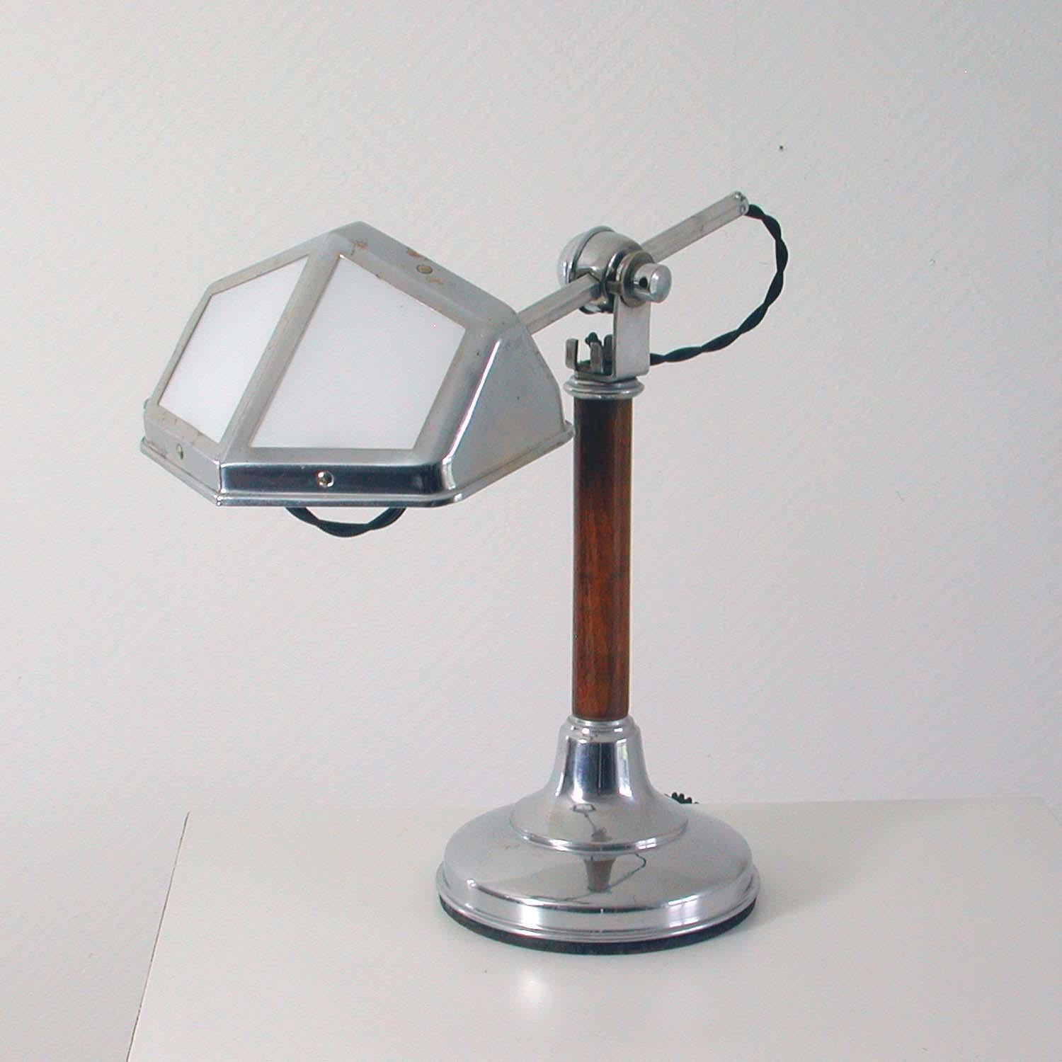 This elegant vintage Pirouette table lamp was manufactured in the French city of Nice in the 1920s during the Art Deco period.

The lamp is made of chrome-plated metal and walnut and has got an adjustable lamp arm and adjustable shade with white