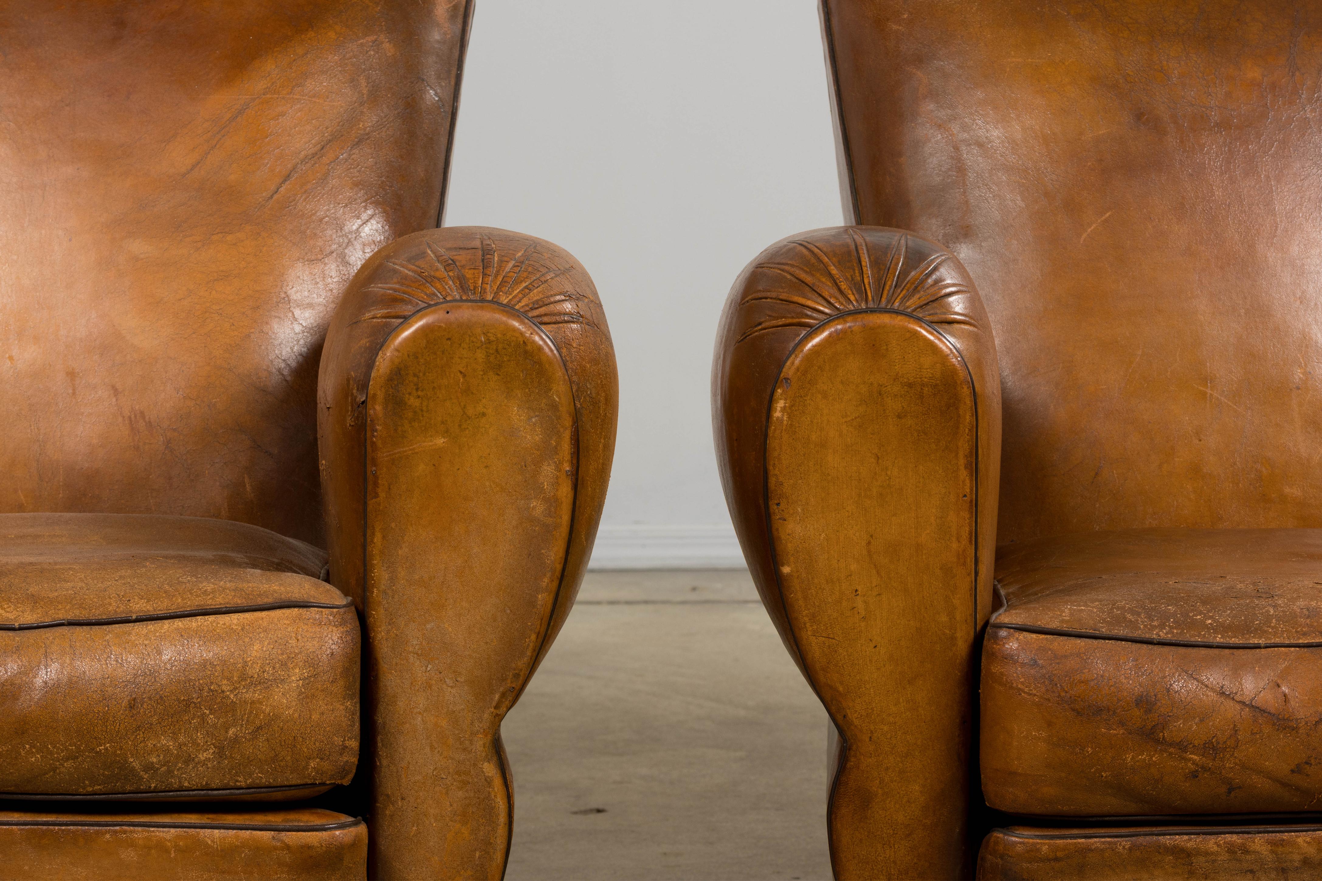 Una tradizionale coppia di sedie da club in pelle Art Déco francese degli anni '20 proveniente dalla Provenza, in Francia. Questi iconici fauteuils club sono caratterizzati da schienali smerlati con silhouette dolcemente arcuate, braccioli