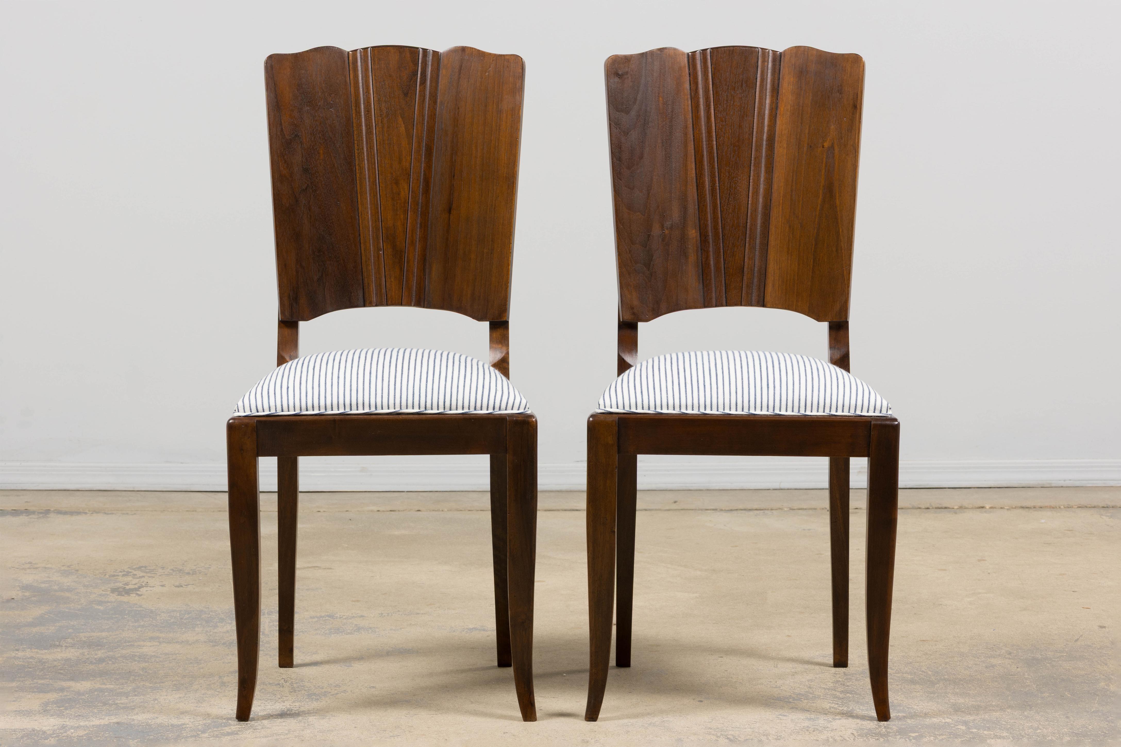 A refined set of six French Art Deco dining chairs sourced in Provence, dating to the late 1920s. The design is defined by sculptural fan-back silhouettes crafted in solid walnut, with gently scalloped crest rails and tapered vertical paneling that