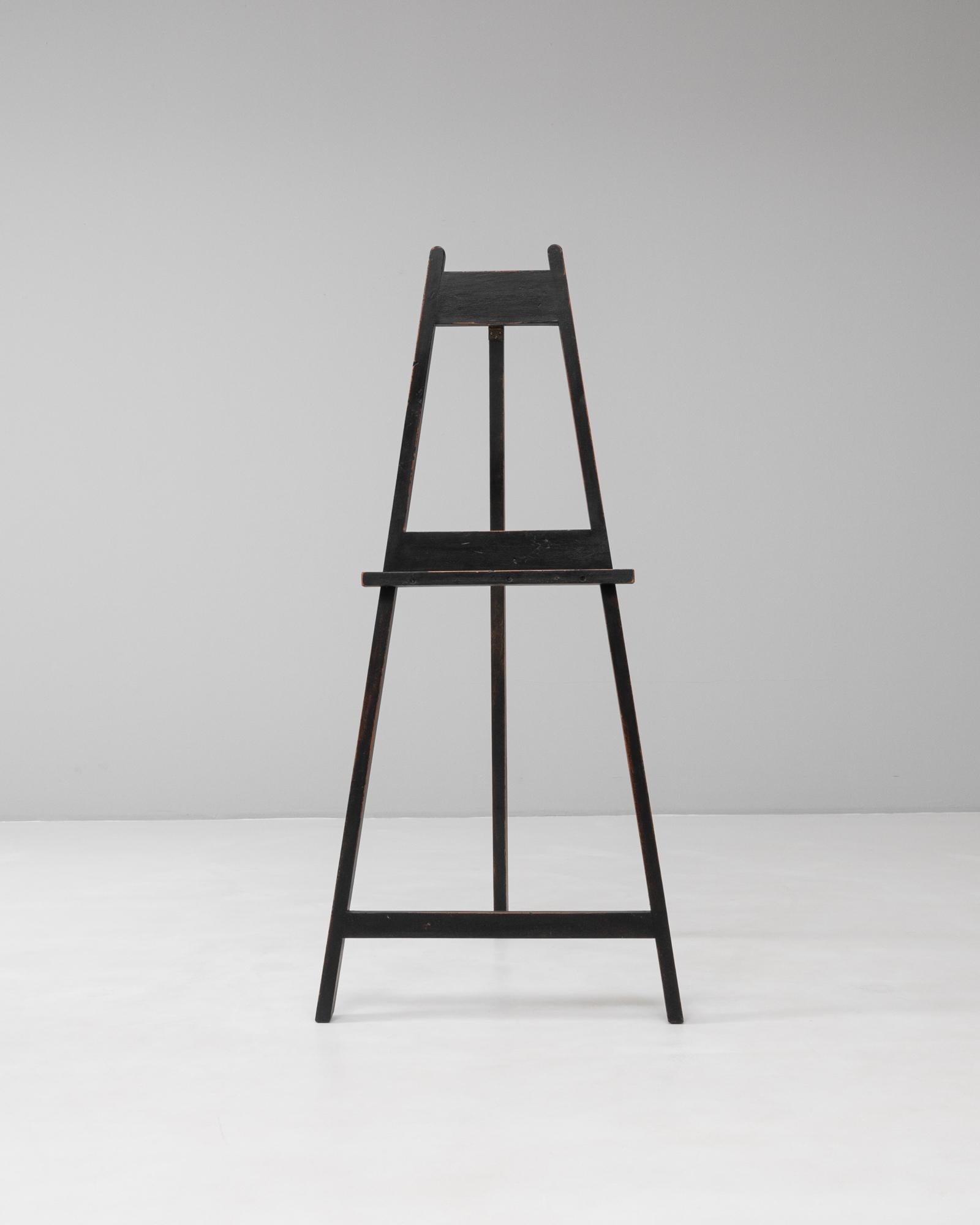 Ce chevalet en bois pour artiste français des années 1920 présente une silhouette architecturale épurée qui reflète la conception pratique des ateliers du début du XXe siècle. Fabriqué en bois teinté foncé avec une surface légèrement usée, il