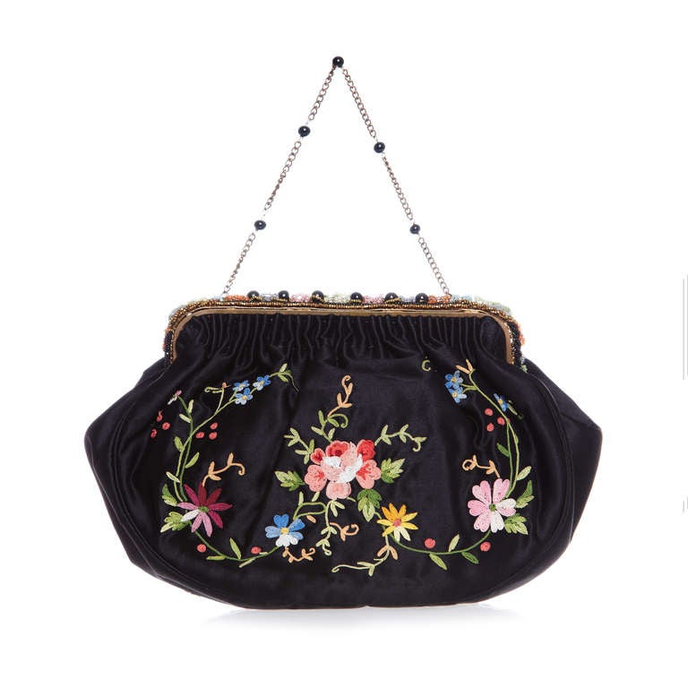 An absolutely stunning 1920s oe early 1930s black silk bag handmade in France with intricate floral crewel work embroidery on both the front and back. The clasp fastening and top edge are beaded in matching colours with a delicate chain and black