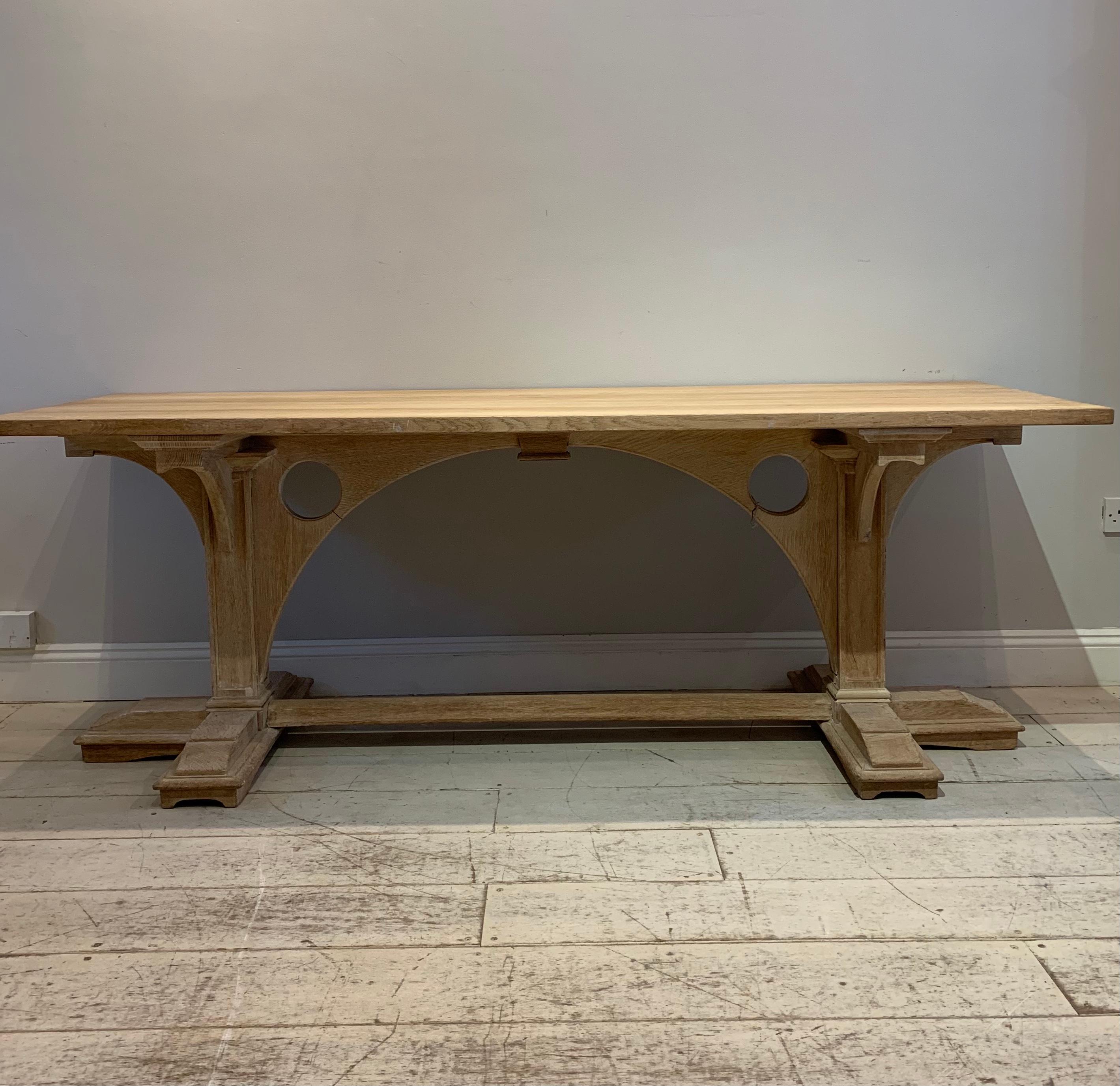A good sized circa 1920s bleached oak refectory table.
The top is a light honey colour which sits on a substantial and interesting base that is both architectural and quite gothic in its design which resembles a bridge
The base support is solid