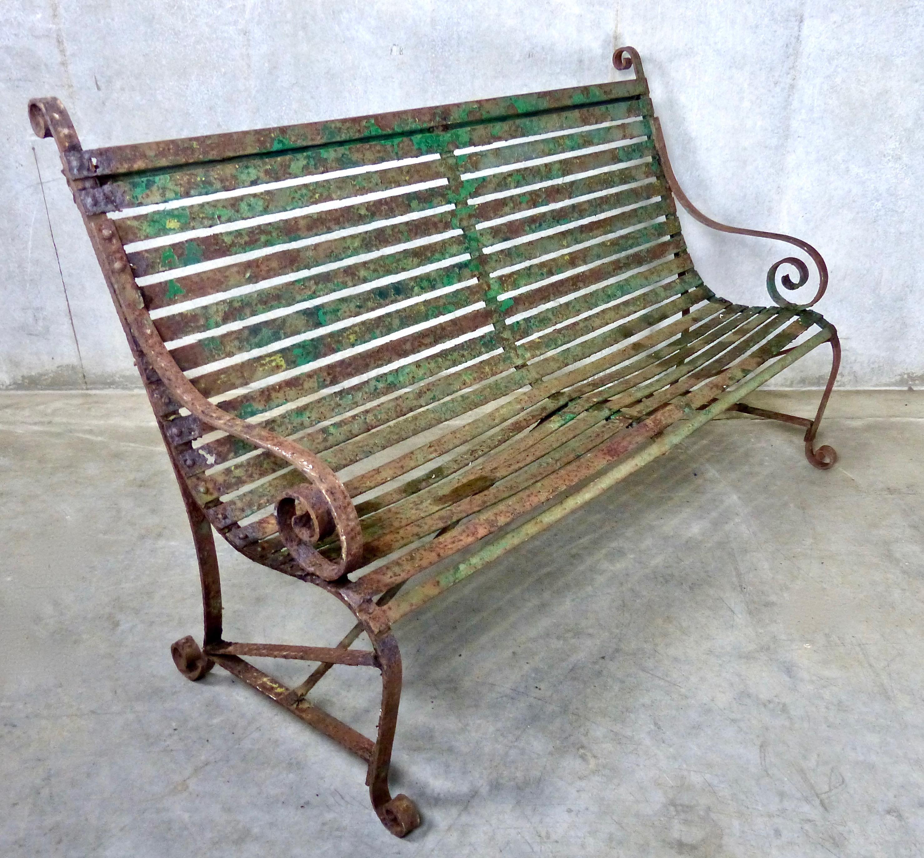 Lovely scrollwork and other decorative details on this antique French garden bench made from forged iron. Retains some of its original green paint for an attractive distressed look.