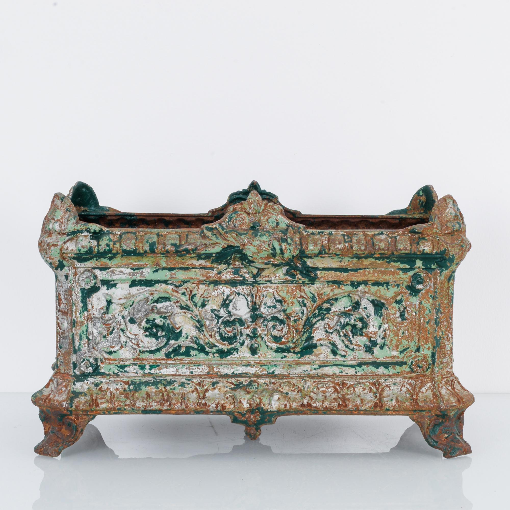 This cast iron planter was made in France, circa 1920. It displays an exquisite patina that shows off its layers of green paint. The planter stands on cabriole legs and features a floral design with intricate decorative details on the rim and bottom.